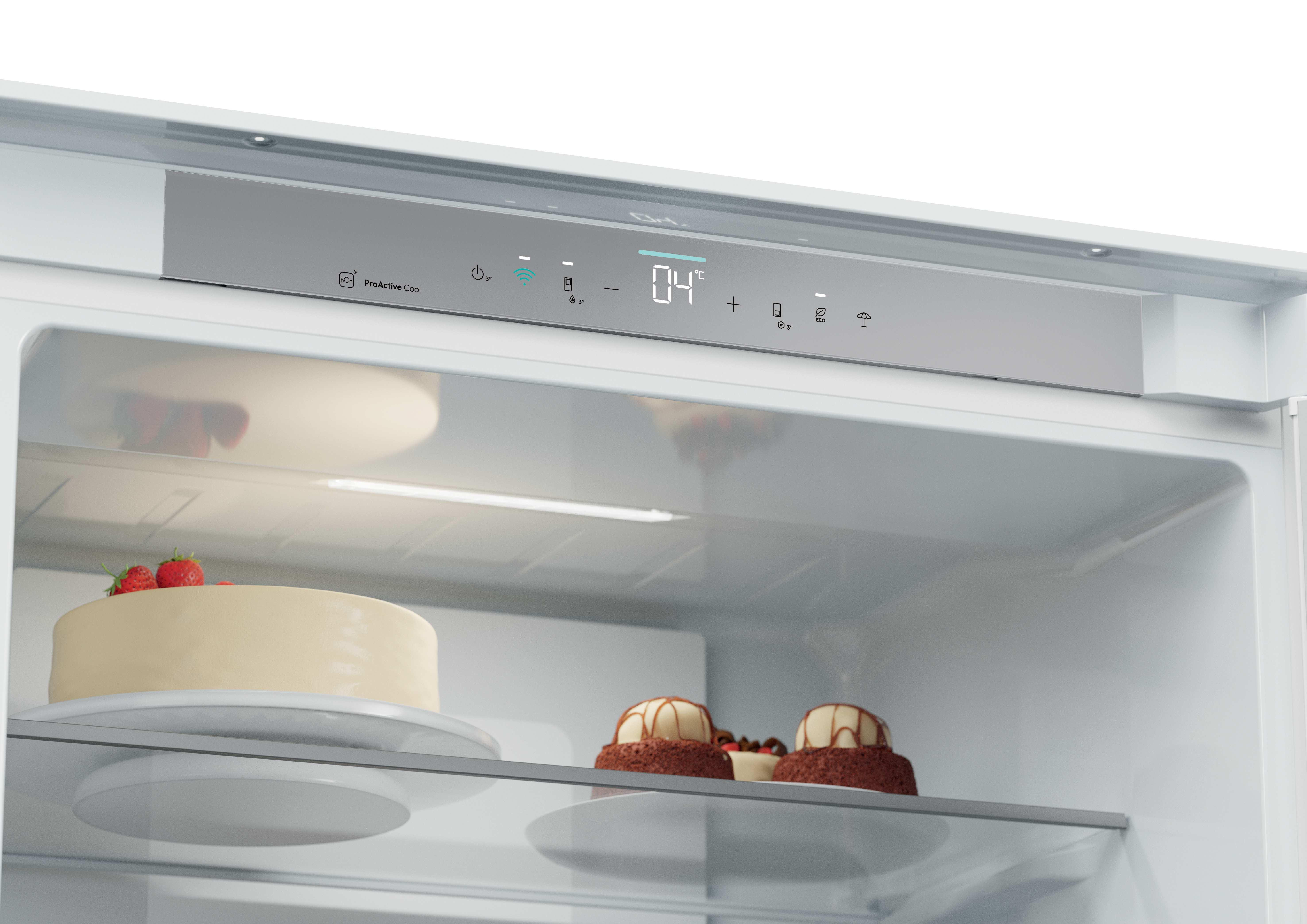 Dentro de la nevera: un pastel con fresas y otros dos pasteles. Un panel muestra la temperatura a 04°C.