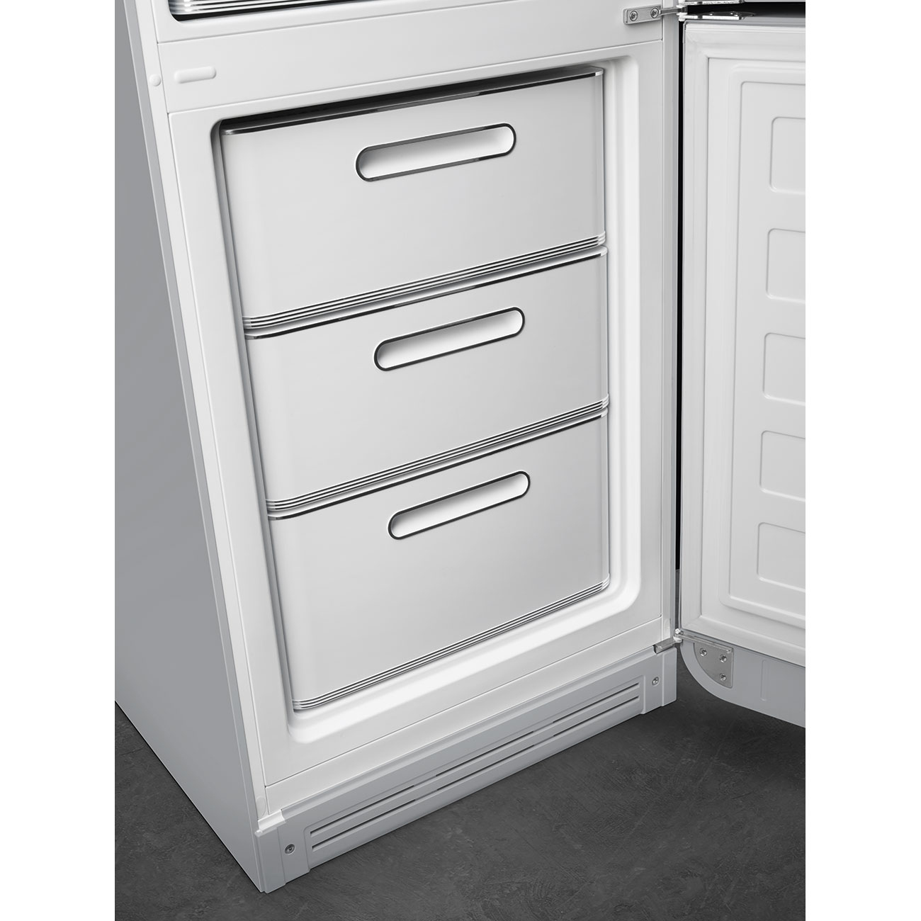 Un refrigerador blanco con la puerta abierta. Se ven tres cajones. La puerta está abierta hacia la derecha. El suelo es oscuro.