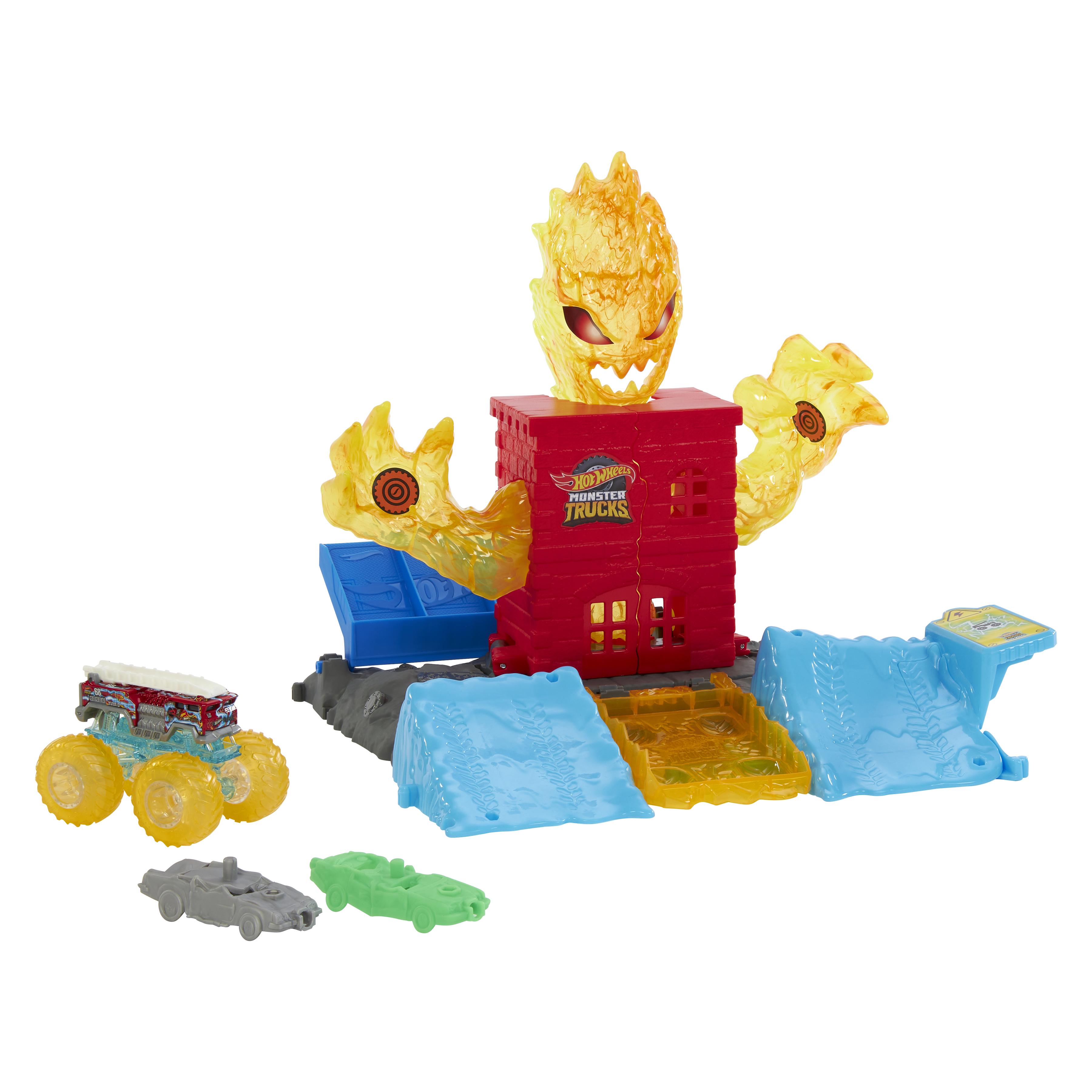 Ein Hot Wheels Monster Trucks Spielset. Es beinhaltet ein rotes Gebäude mit feuerähnlichem Kopf, Rampen und Spielzeugautos.