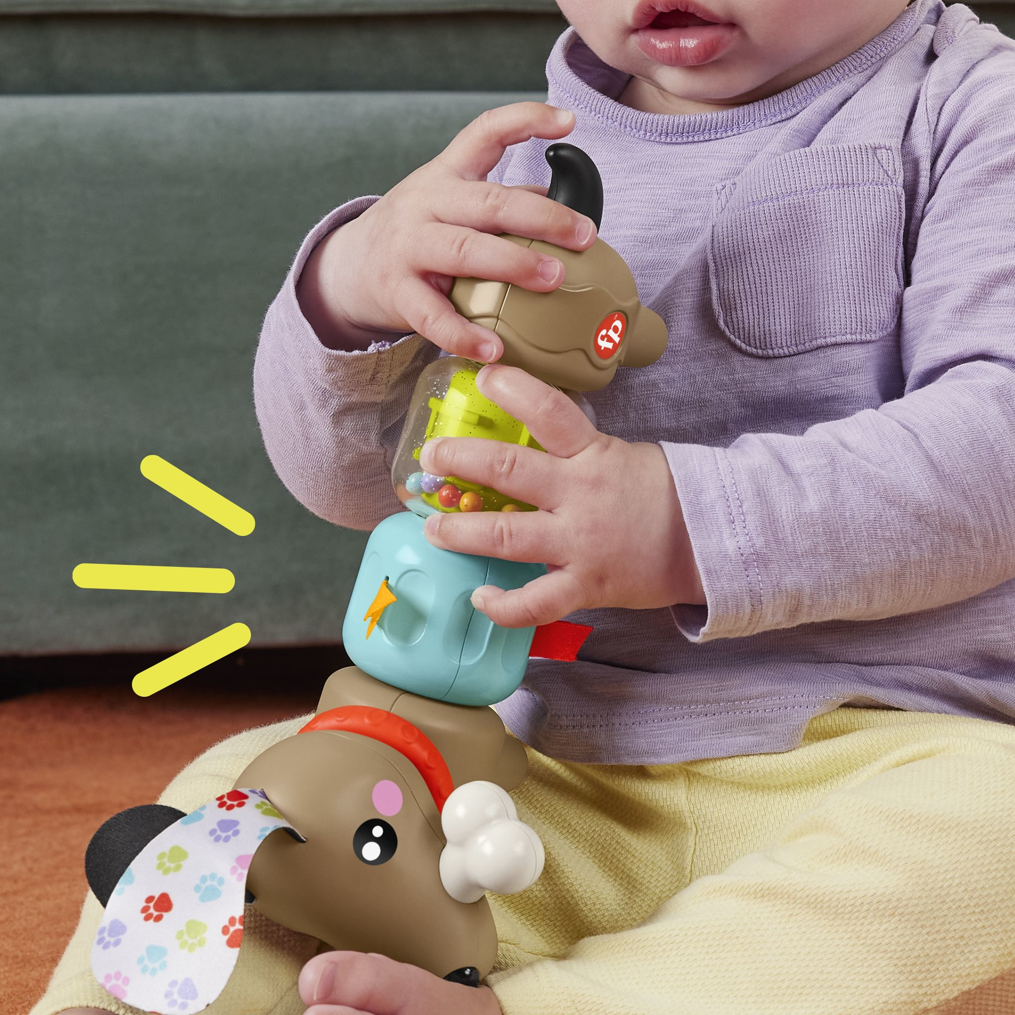 Baby spielt mit einem gestapelten Hundespielzeug. Das Spielzeug hat mehrere Abschnitte mit verschiedenen Farben und Formen.