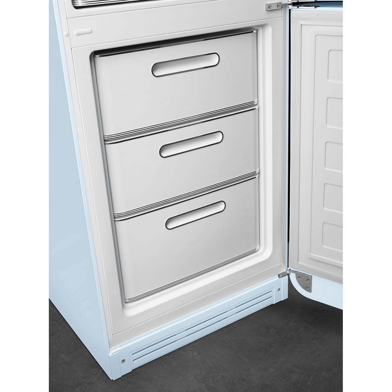 Primer plano de un refrigerador azul claro con la puerta abierta. Se ven tres cajones dentro, cada uno con un asa plateada.