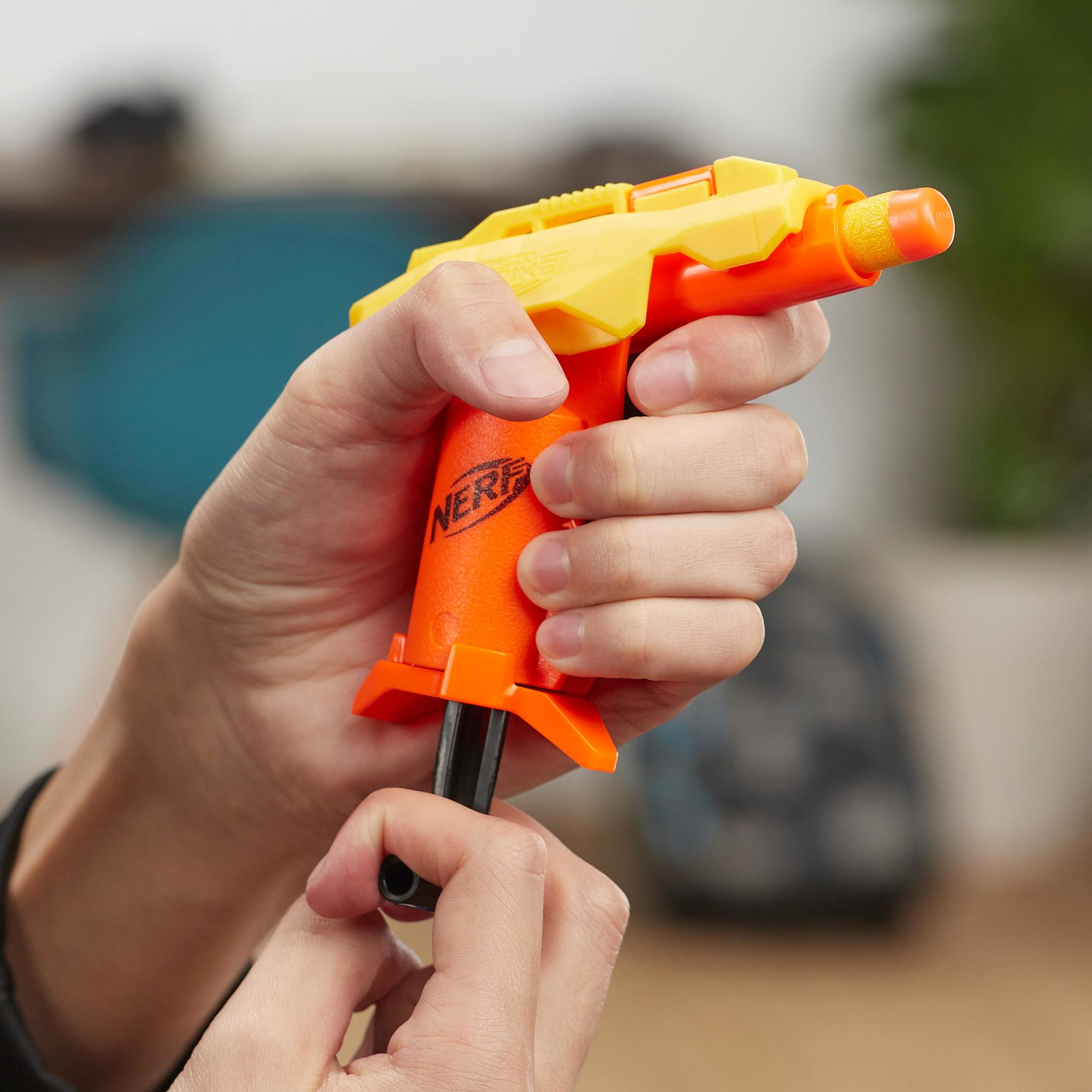 Eine Person hält eine orangefarbene und gelbe Nerf-Pistole. Die Waffe wird für den Gebrauch vorbereitet. Der Hintergrund ist unscharf.