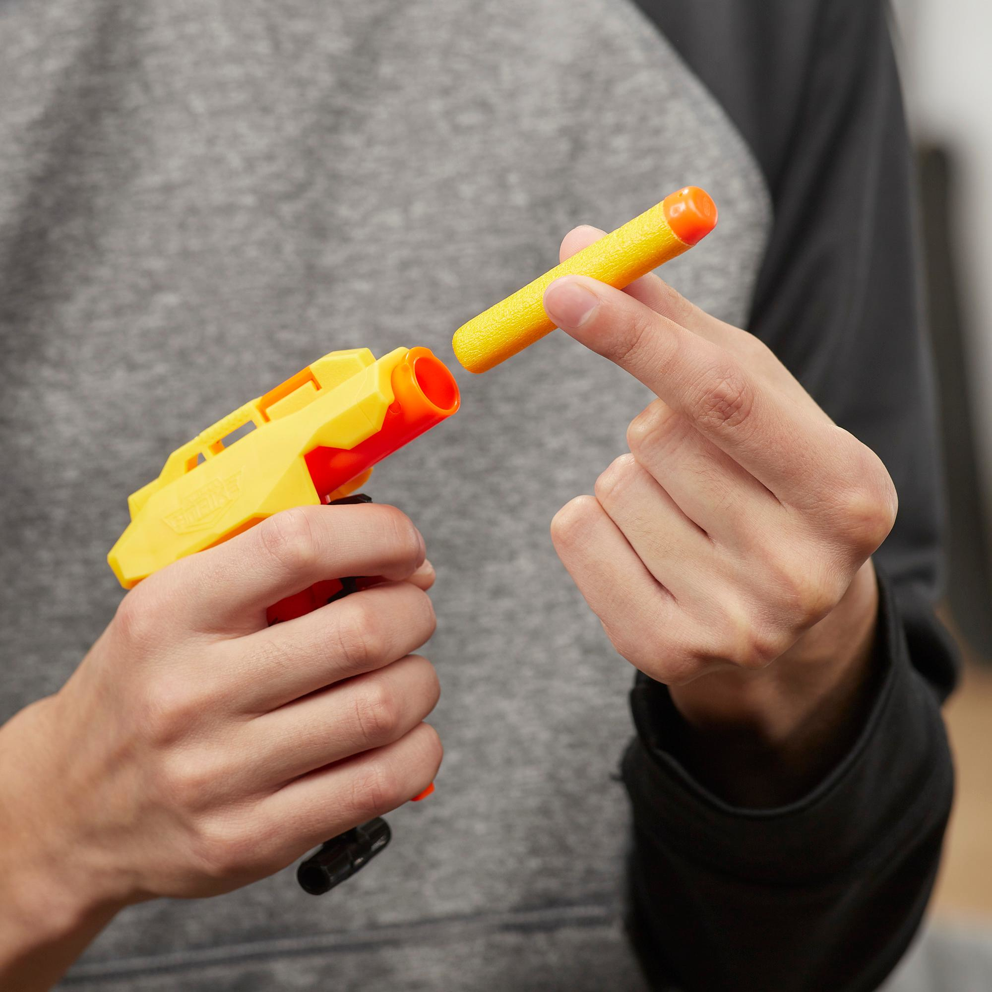 Person hält eine gelbe Spielzeugpistole und einen gelben Pfeil mit orangefarbener Spitze und bereitet das Laden vor.