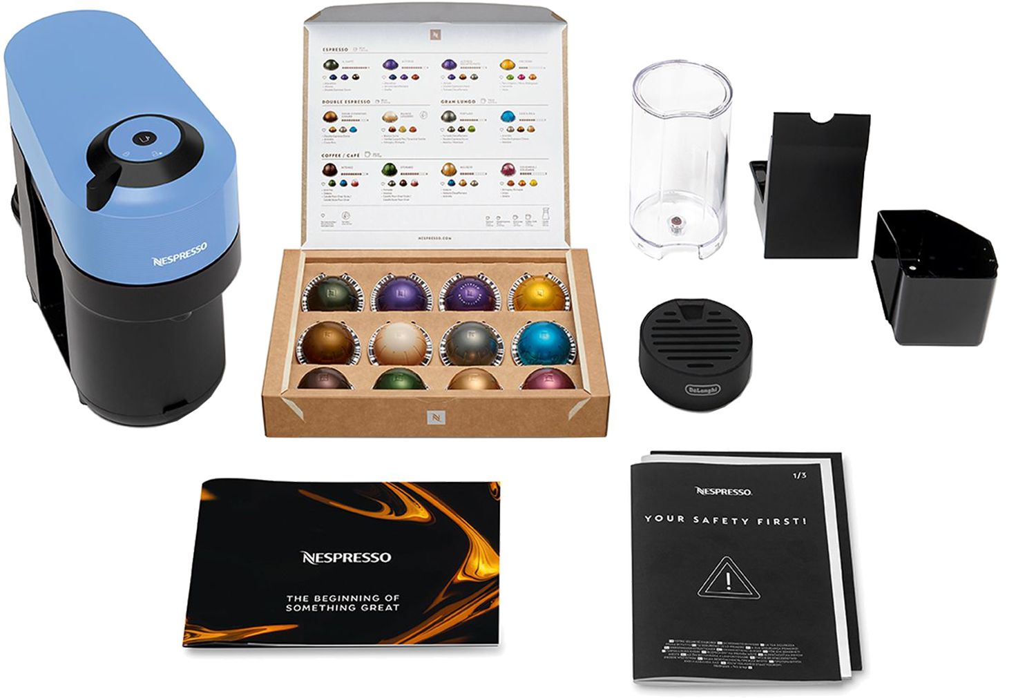 Ekspres do kawy Nespresso z kapsułkami, akcesoriami i instrukcjami. Zawiera niebiesko-czarną maszynę, pudełko na kapsułki i broszury.