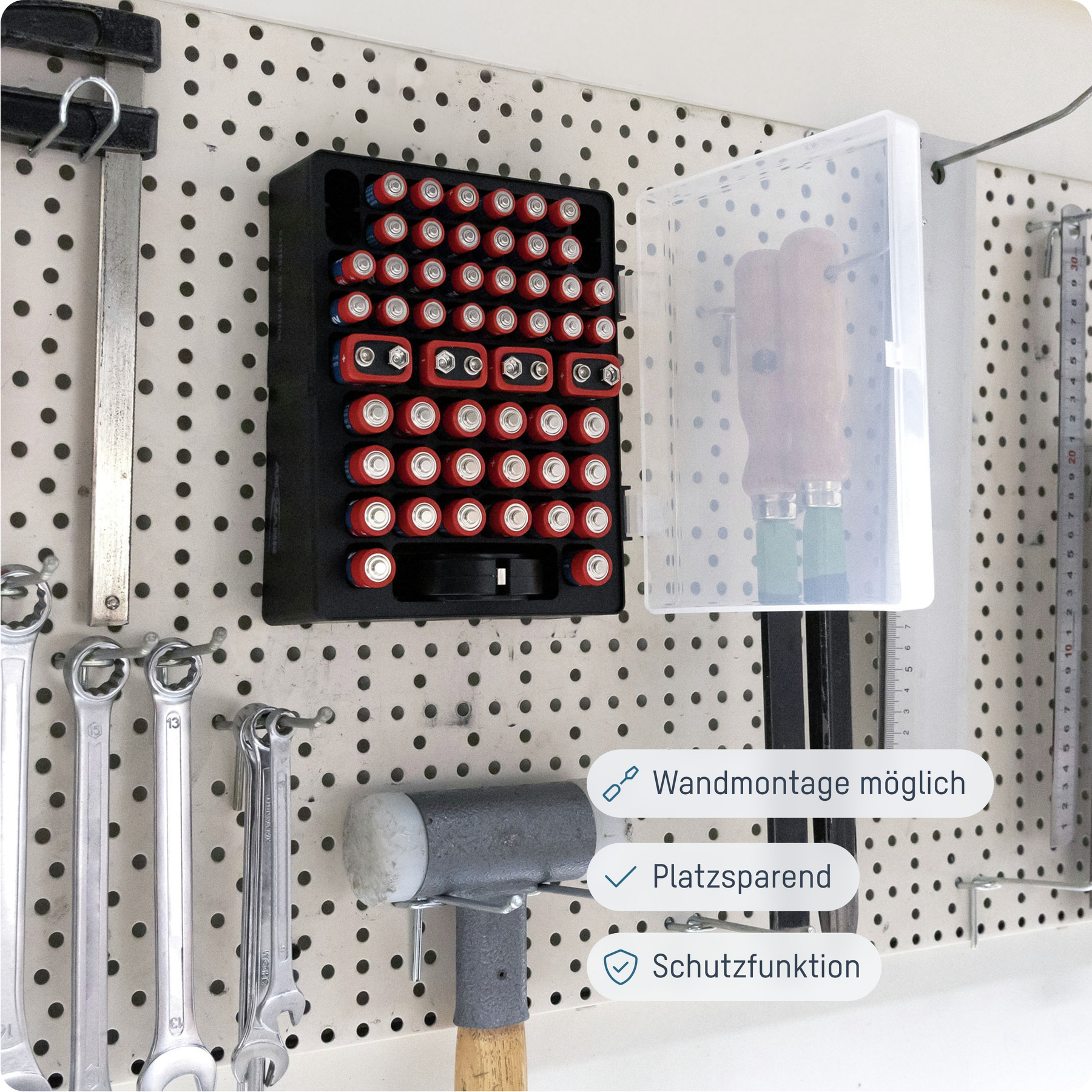 Eine Lochwand mit Werkzeugen und Batterien. Ein schwarzer Batterie-Organizer hat rote und silberne Batterien. Andere Werkzeuge sind zu sehen.
