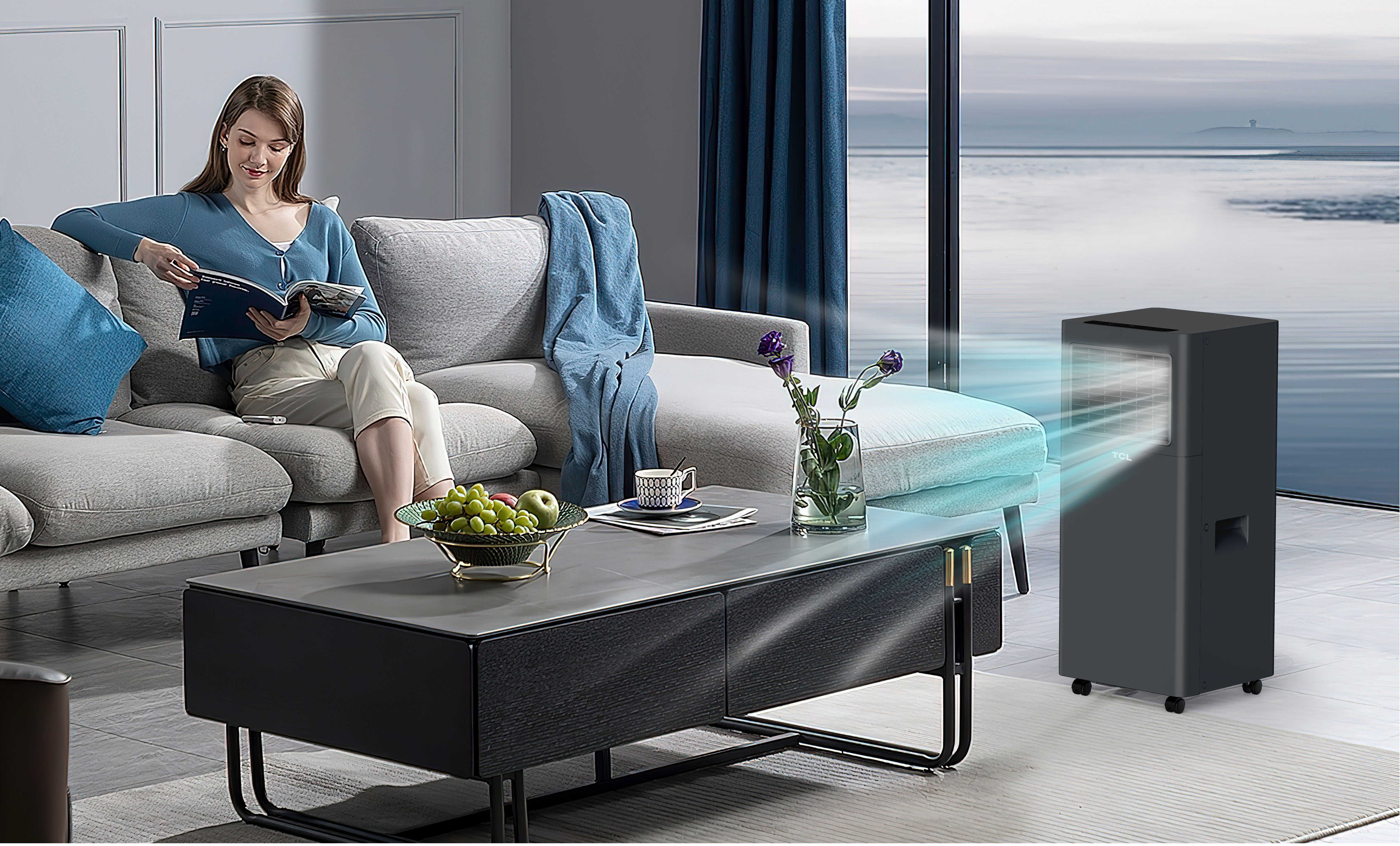 Kobieta czyta na szarej sofie. Stolik kawowy z owocami i wazonem. Klimatyzator TCL w tle.