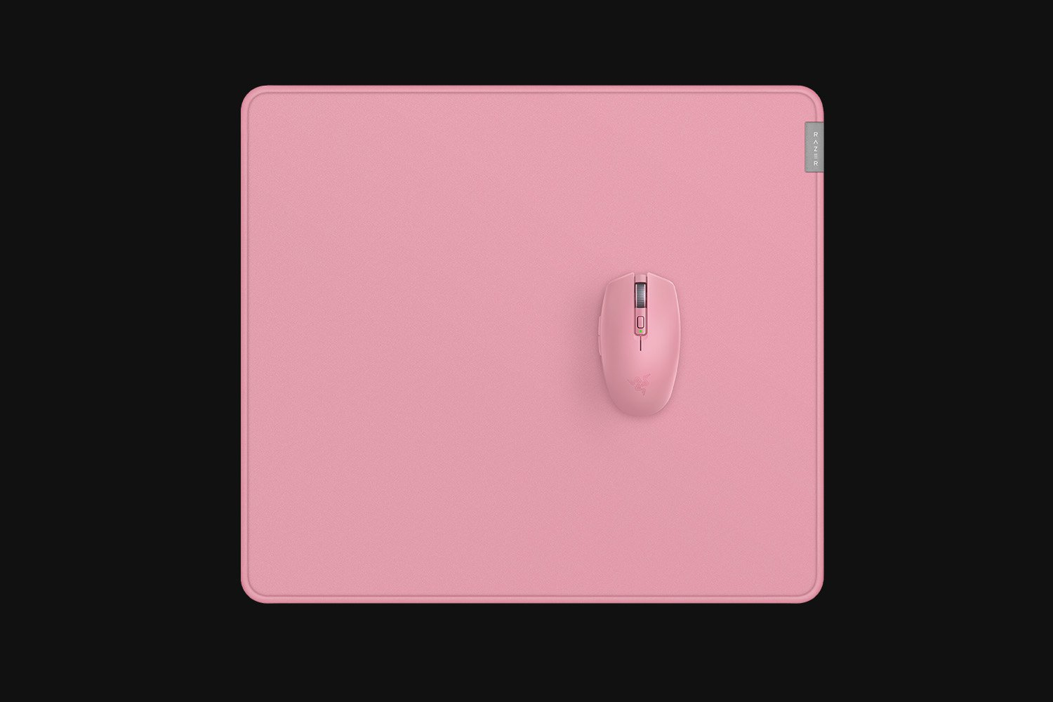 Różowa mysz na różowej podkładce, obie na czarnym tle. Widoczne logo Razer na myszy i podkładce.