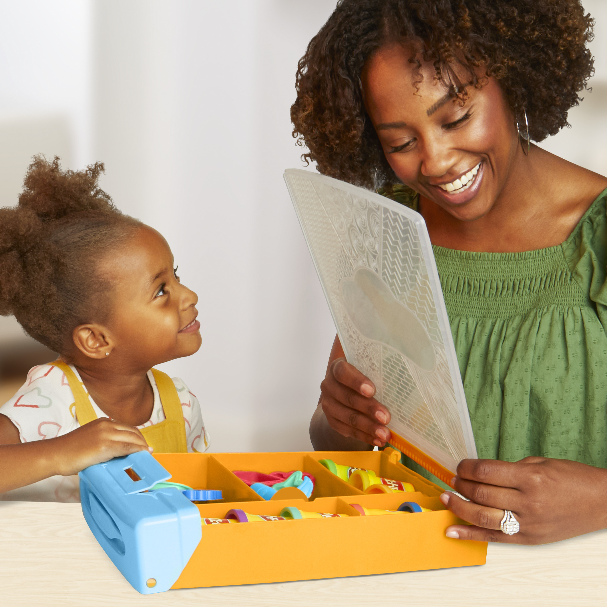 Kobieta i dziewczynka patrzą na plastikową tacę z zabawkami. Kobieta trzyma przezroczystą plastikową folię.