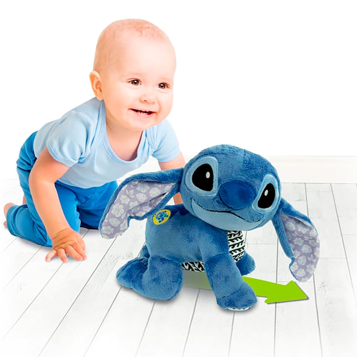 Niemowlę raczkuje w kierunku niebieskiej pluszowej zabawki Stitch. Zabawka ma duże uszy i strzałkę wskazującą w prawo.