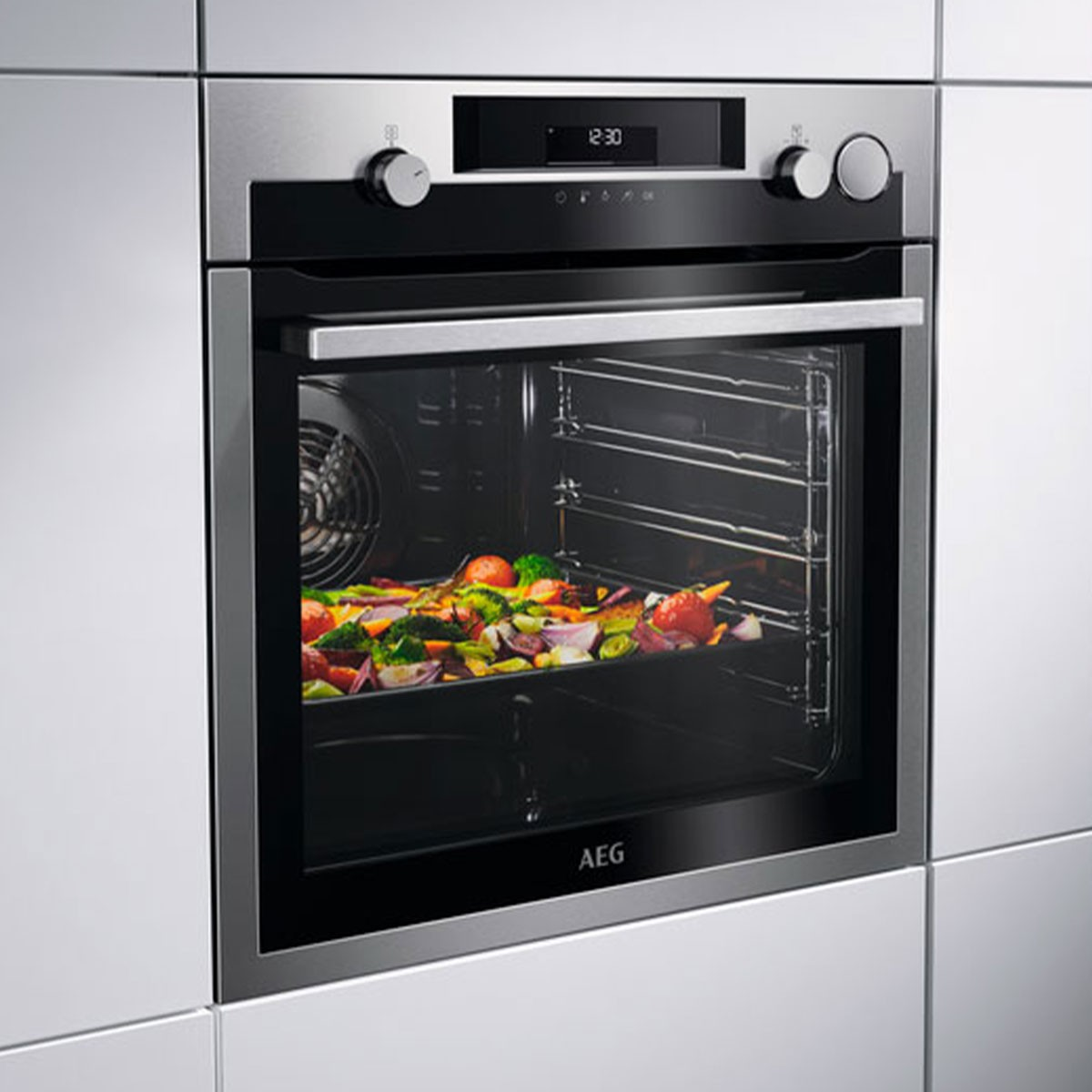 Un forno AEG con verdure arrostite all'interno. Il forno è a incasso, con orologio digitale. Manopole a sinistra e a destra.