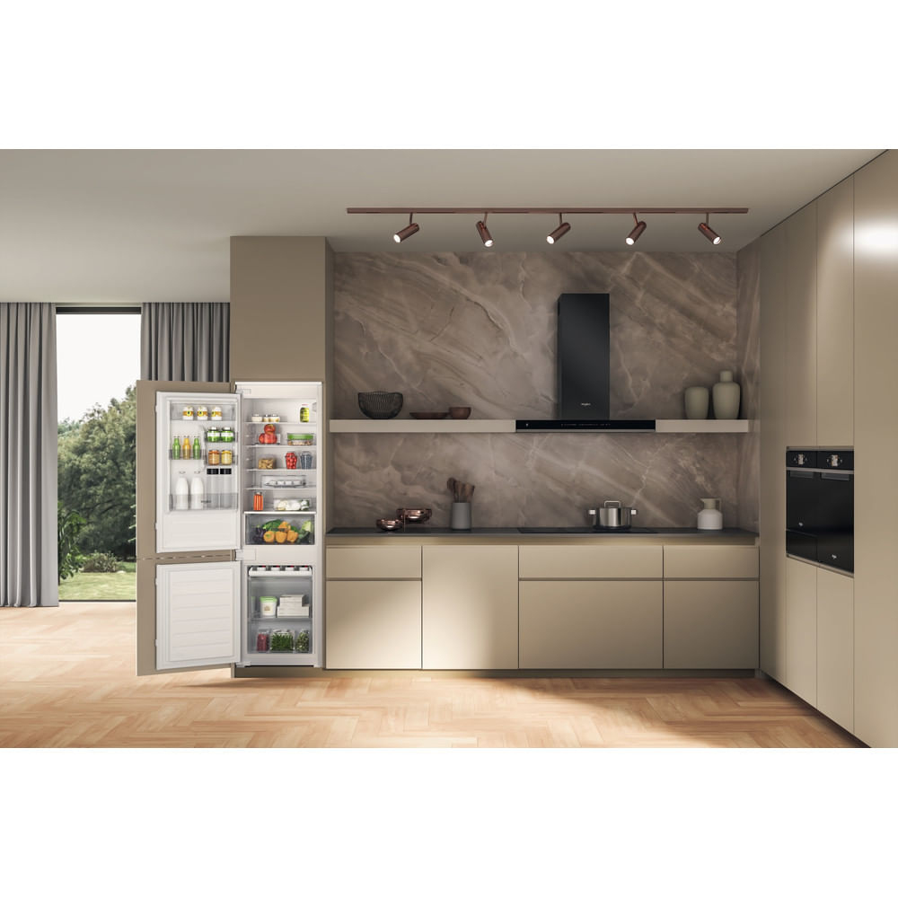 Una cucina moderna con frigorifero aperto. All'interno del frigorifero ci sono vari alimenti. La cucina ha mobili colorati chiari e un paraschizzi in marmo.
