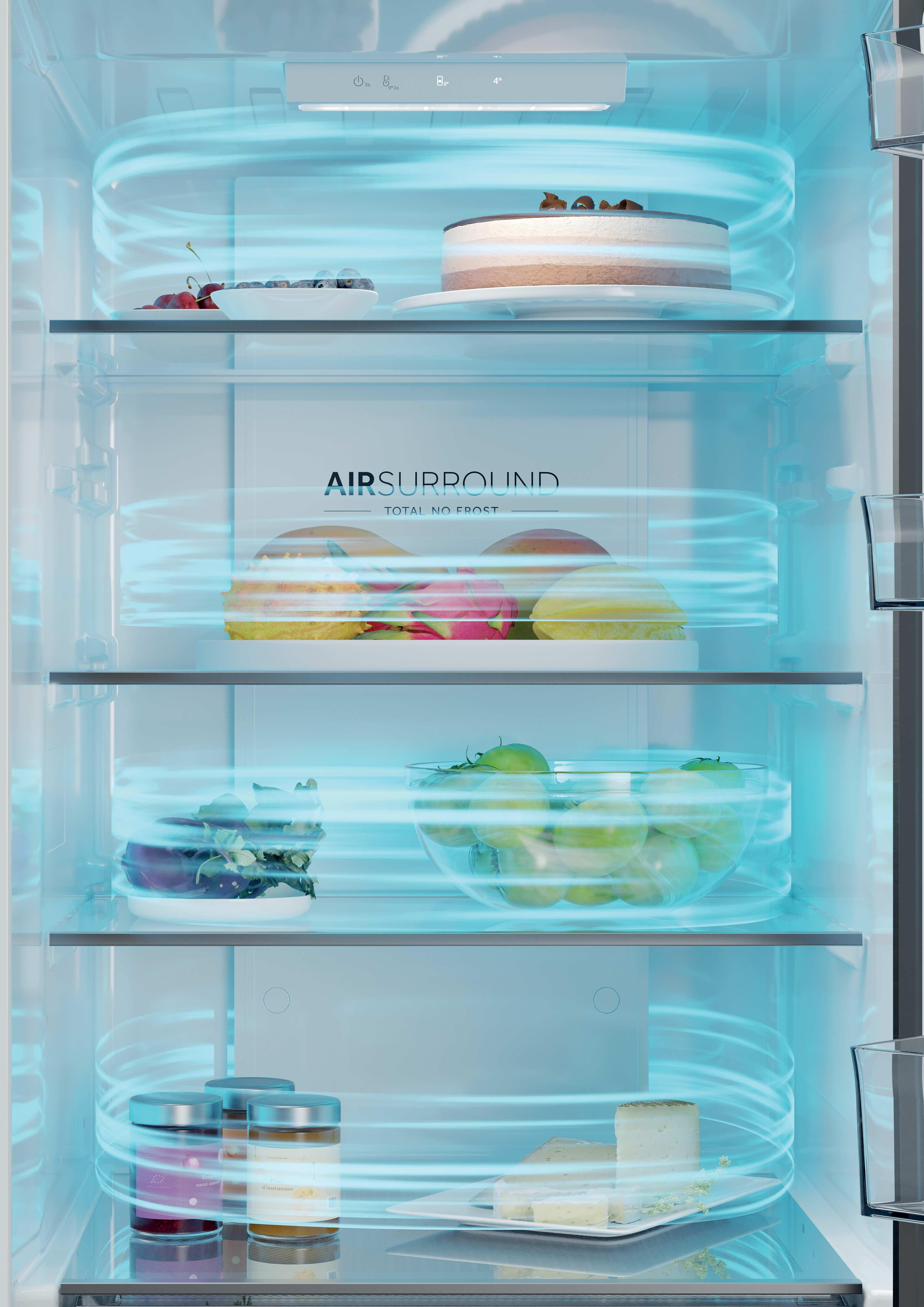 Otwarta lodówka wypełniona jedzeniem. Widoczne ciasto, owoce, ser i słoiki. Wewnątrz wiruje niebieskie światło.