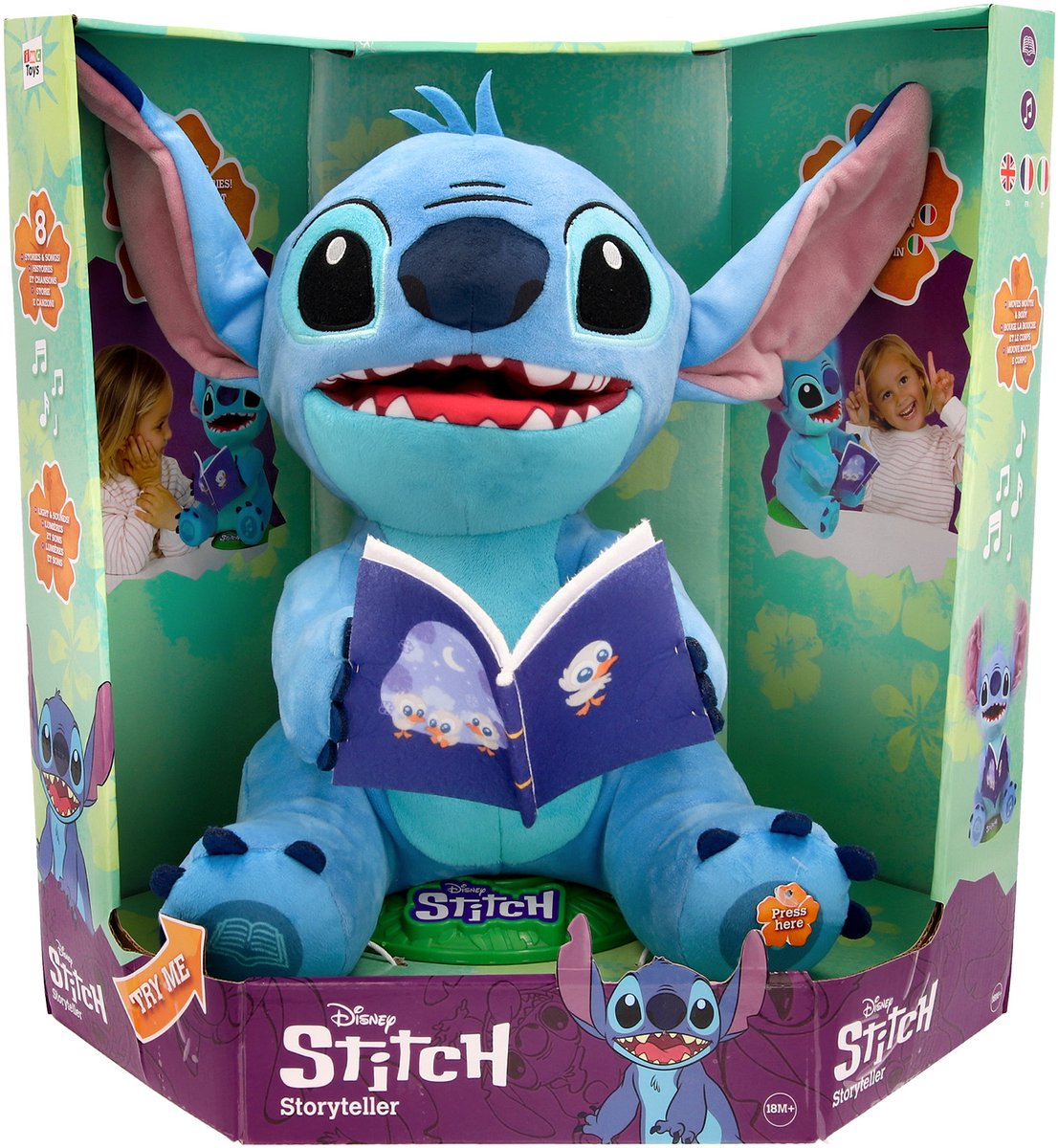 Ein Stitch-Plüschtier sitzt in einer Box und hält ein Buch. Die Box zeigt Stitch-Illustrationen und einen Knopf mit der Aufschrift 'Hier drücken'.