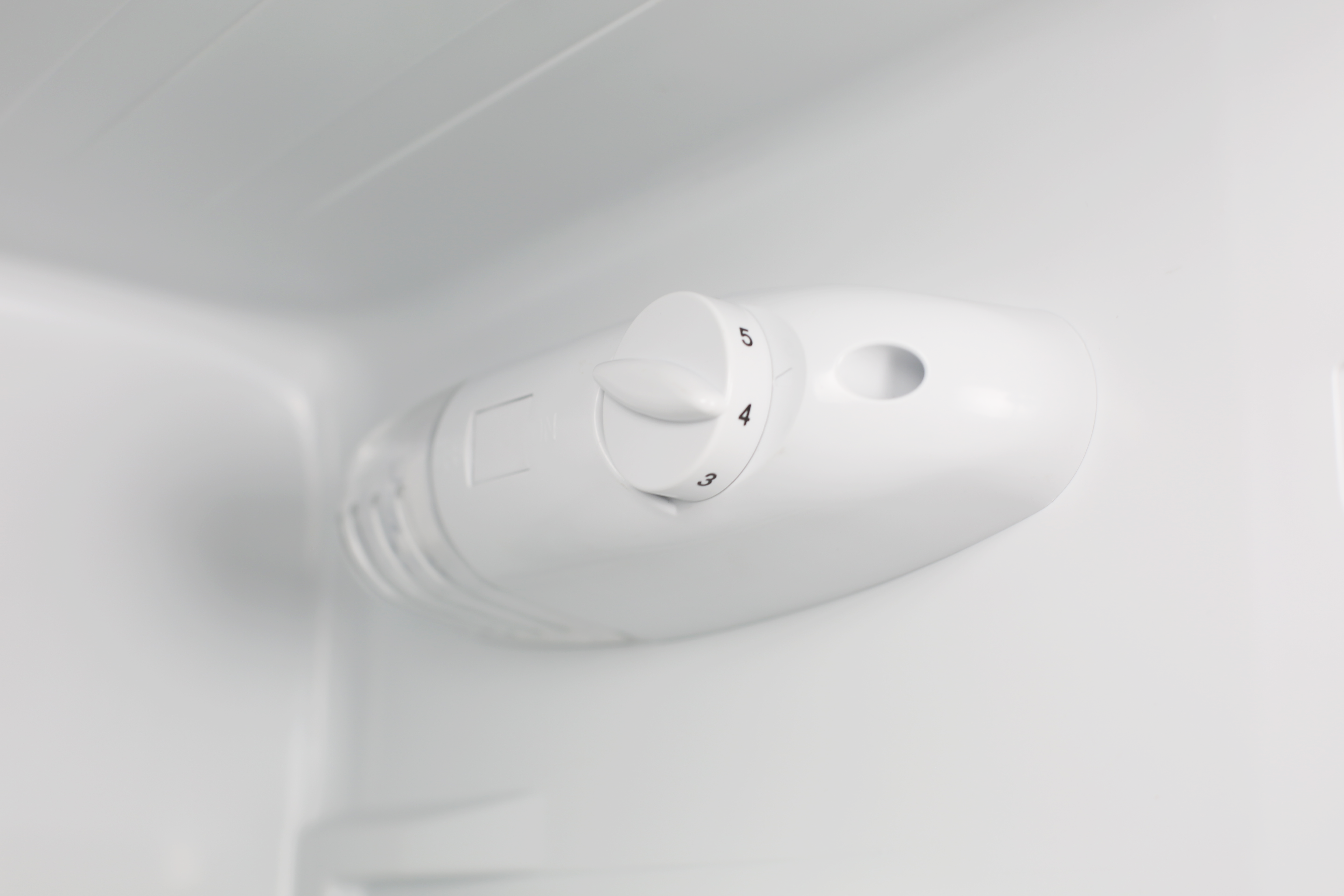 Dentro de un refrigerador, un panel de control blanco con los números 3, 4 y 5 en un dial. El interior es blanco.