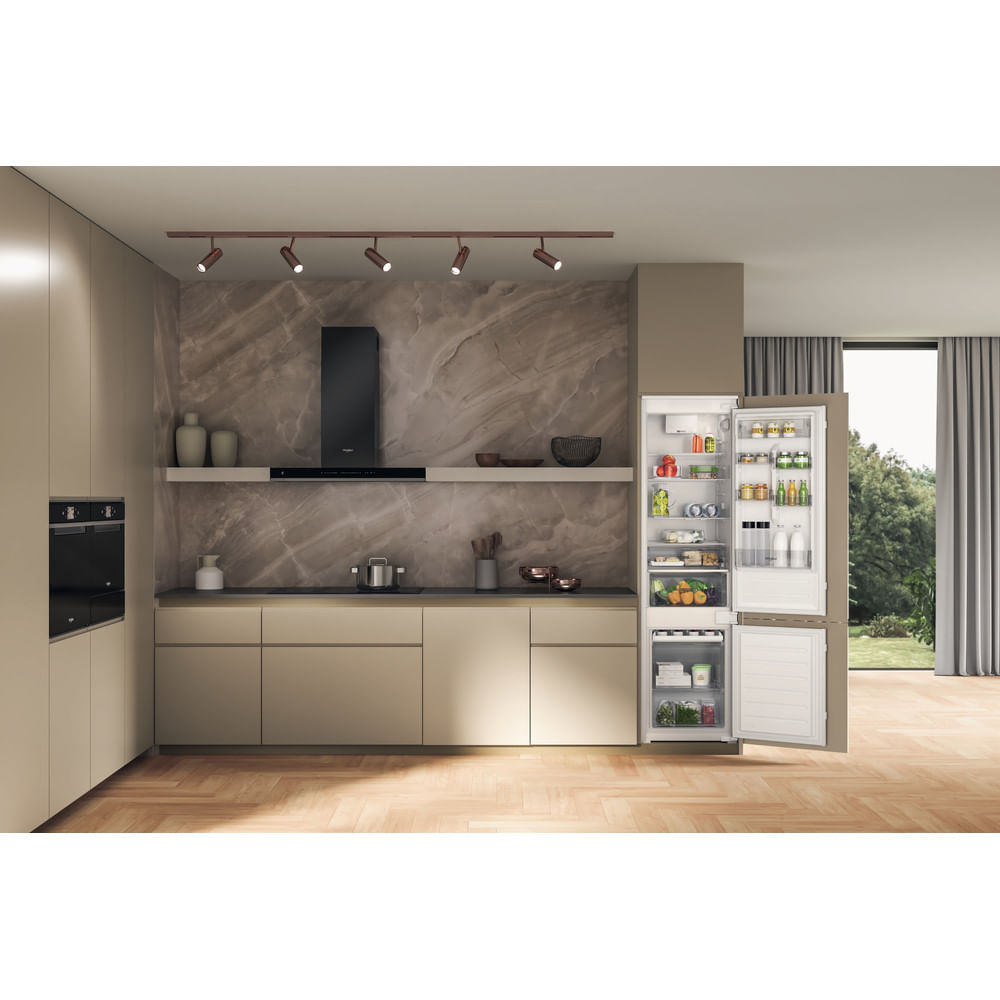 Una cucina moderna con frigorifero aperto. All'interno ci sono generi alimentari. Una cappa nera è sopra un bancone. Pavimento in legno.