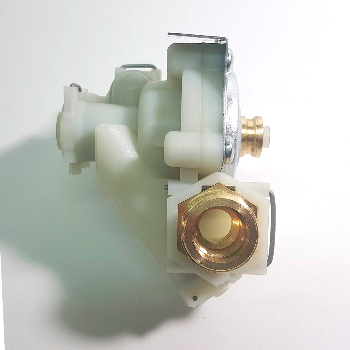 Primer plano de una válvula de agua. Tiene componentes de plástico blanco, accesorios de latón y una placa de metal. Está sobre una superficie blanca.