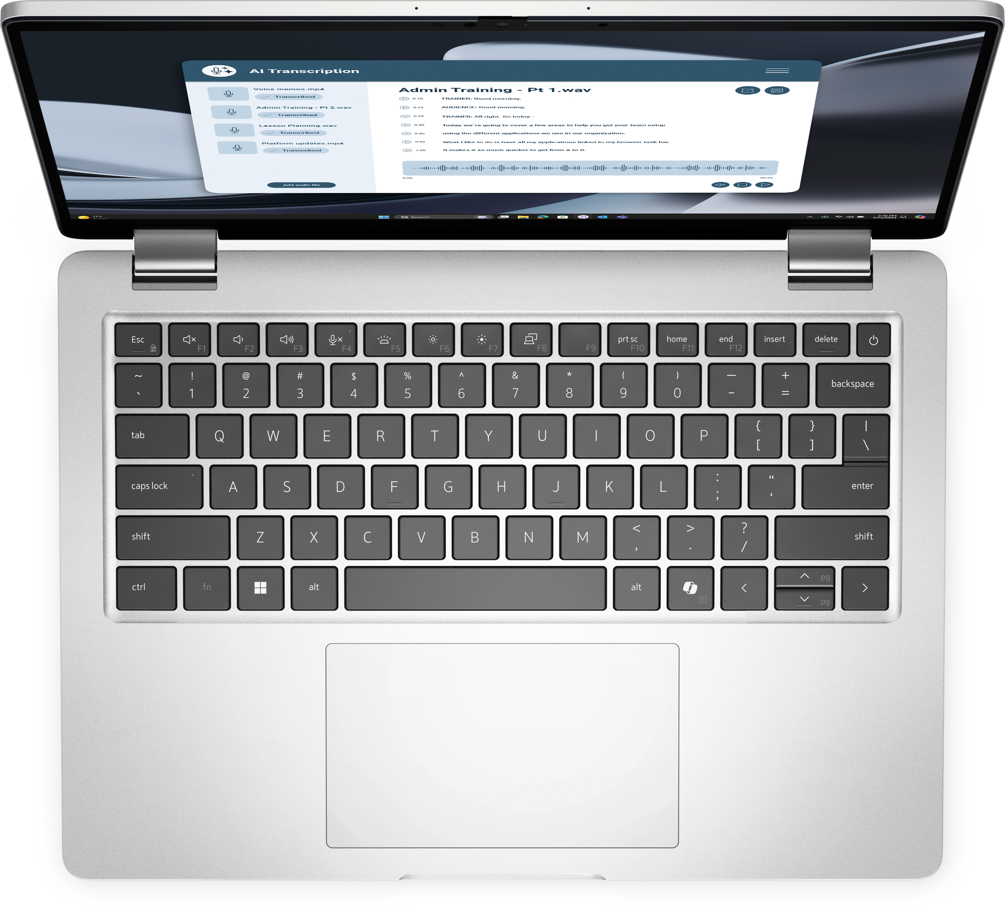 Otwarty laptop, pokazujący aplikację do transkrypcji. Widoczna klawiatura. Srebrna obudowa.