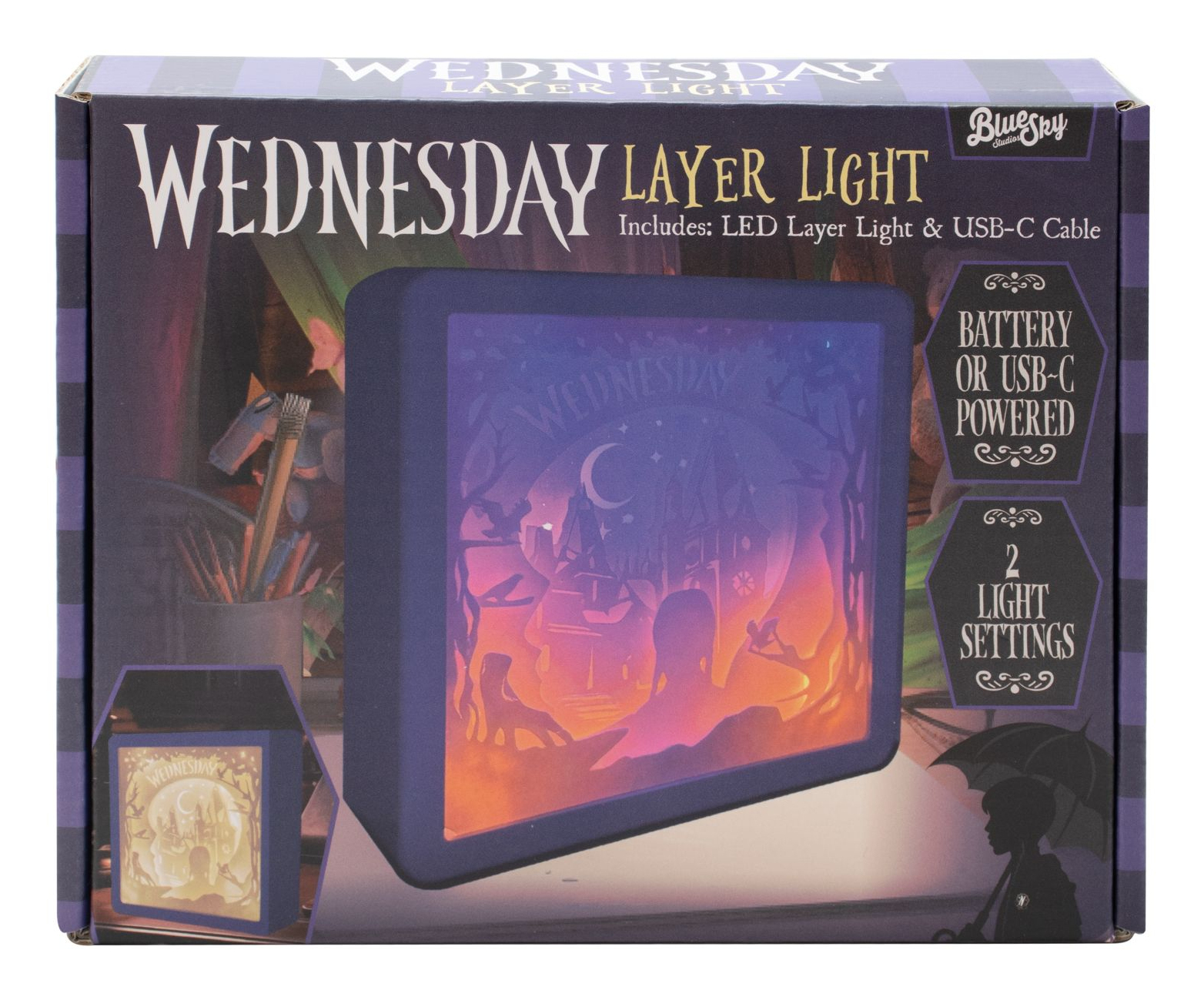 Pudełko przedstawia lampę warstwową z motywem „Wednesday”. Ma sylwetkę zamku, postaci i półksiężyca.