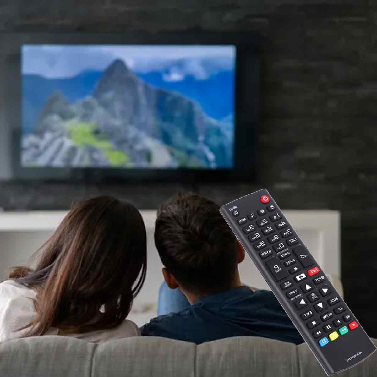 Zwei Personen auf einem Sofa sehen fern. Eine Fernbedienung befindet sich im Vordergrund. Der Fernseher zeigt einen Berg.