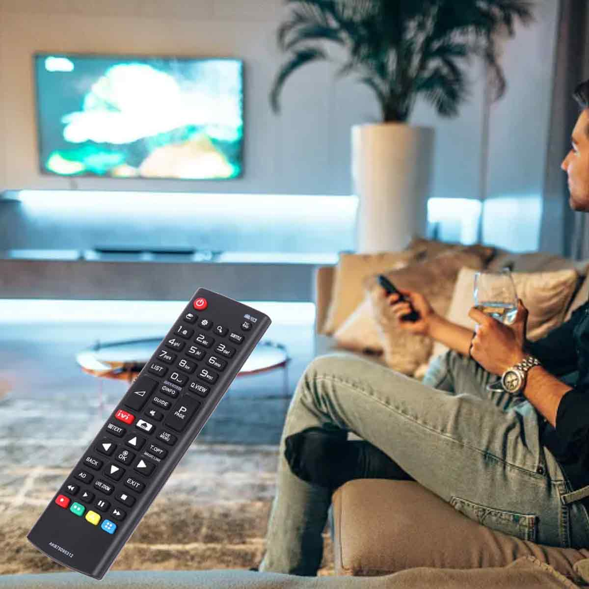 Eine Person sitzt auf einem Sofa, hält eine Fernbedienung und ein Glas. Ein Fernsehbildschirm ist an. Eine Fernbedienung ist im Vordergrund.