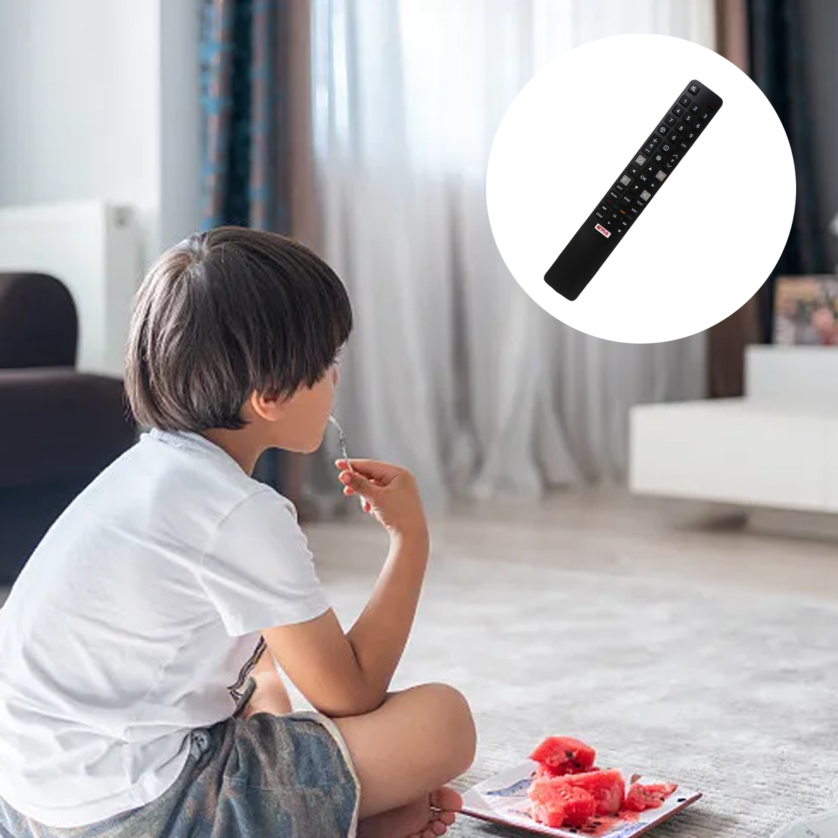 Ein Junge isst Wassermelone, mit einer TV-Fernbedienung in einem Kreis. Die Szene ist drinnen. Im Hintergrund ist ein weißer Schrank zu sehen.