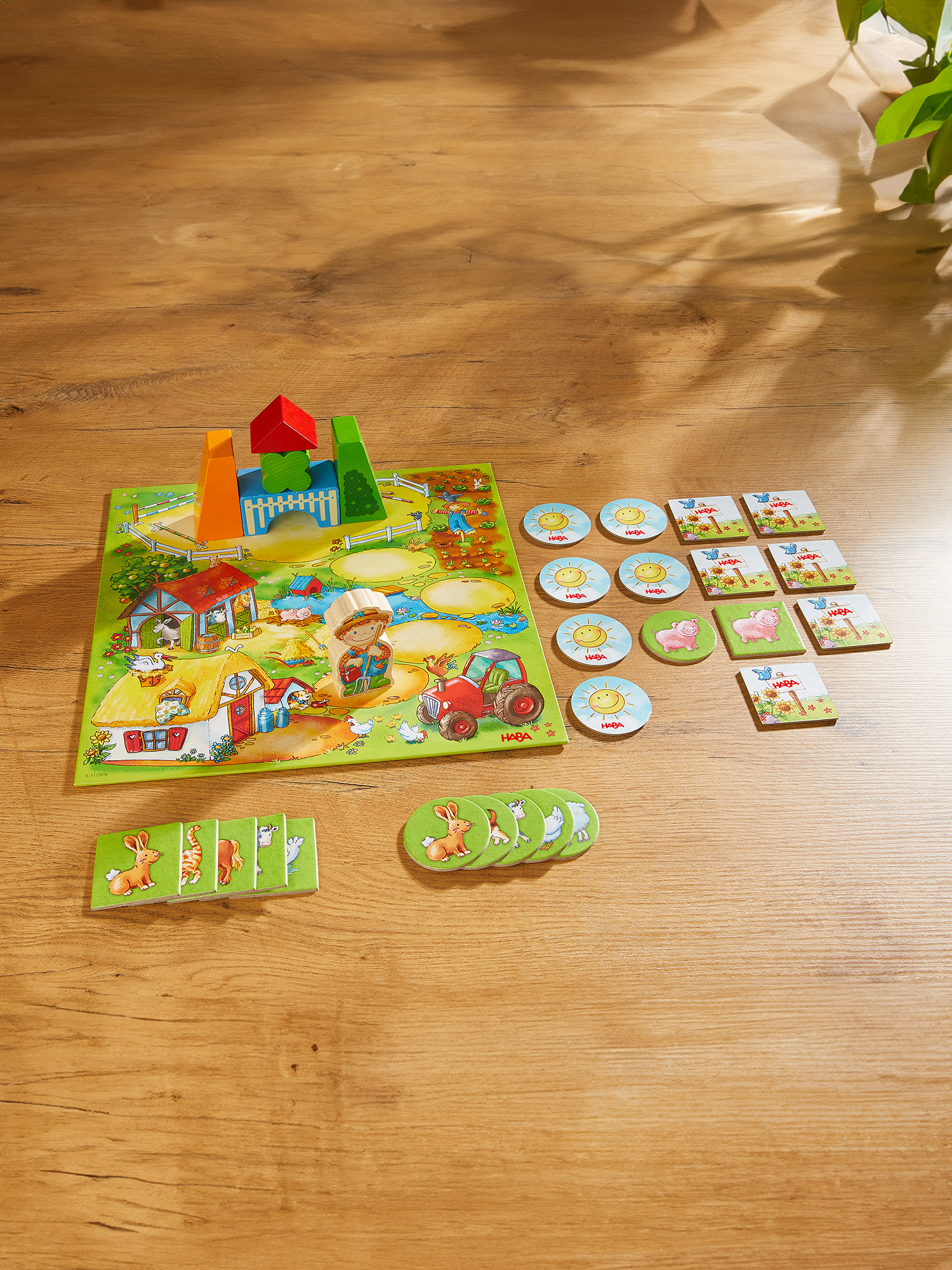 Ein Brettspiel zum Thema Bauernhof mit einem Brett, Holzklötzen und Tierkacheln auf einer Holzoberfläche.