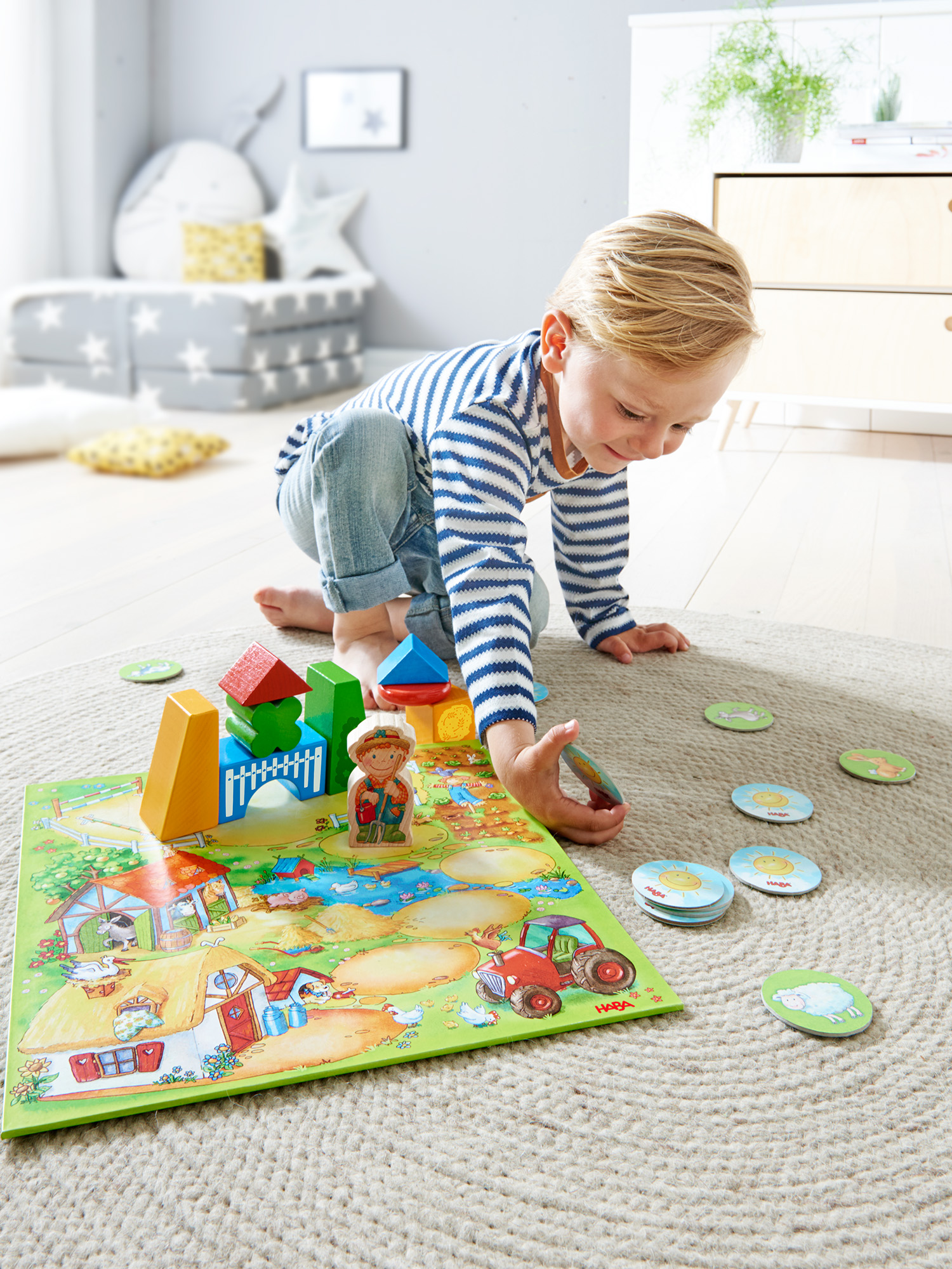 Ein Kind spielt ein Brettspiel zum Thema Bauernhof mit Holzblöcken und Spielsteinen auf einem Teppich. Die Szene umfasst eine Bauernhof-Illustration.