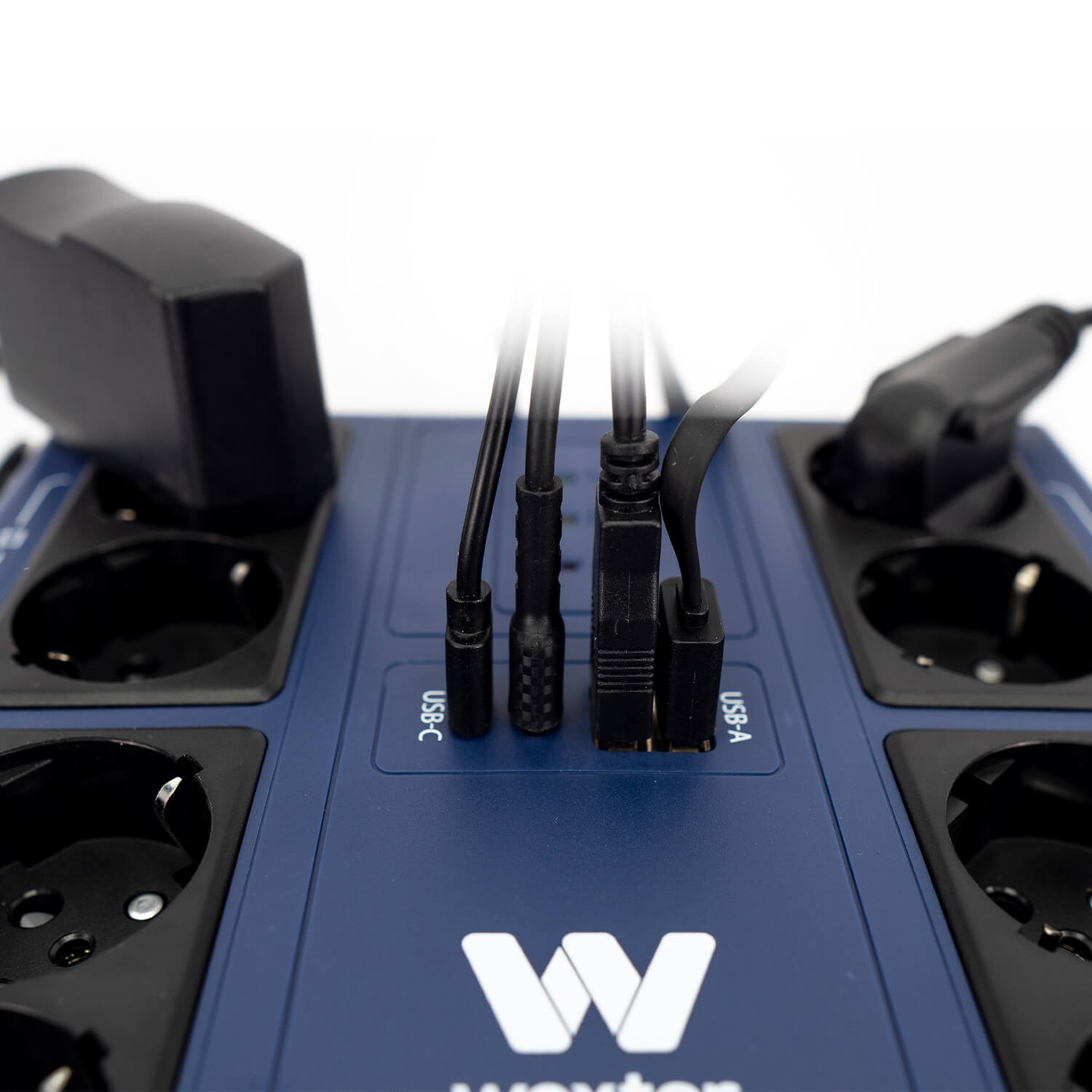 Una regleta azul con múltiples enchufes y puertos USB. Hay enchufes y cables negros conectados. Se ve la marca 'Wexter'.