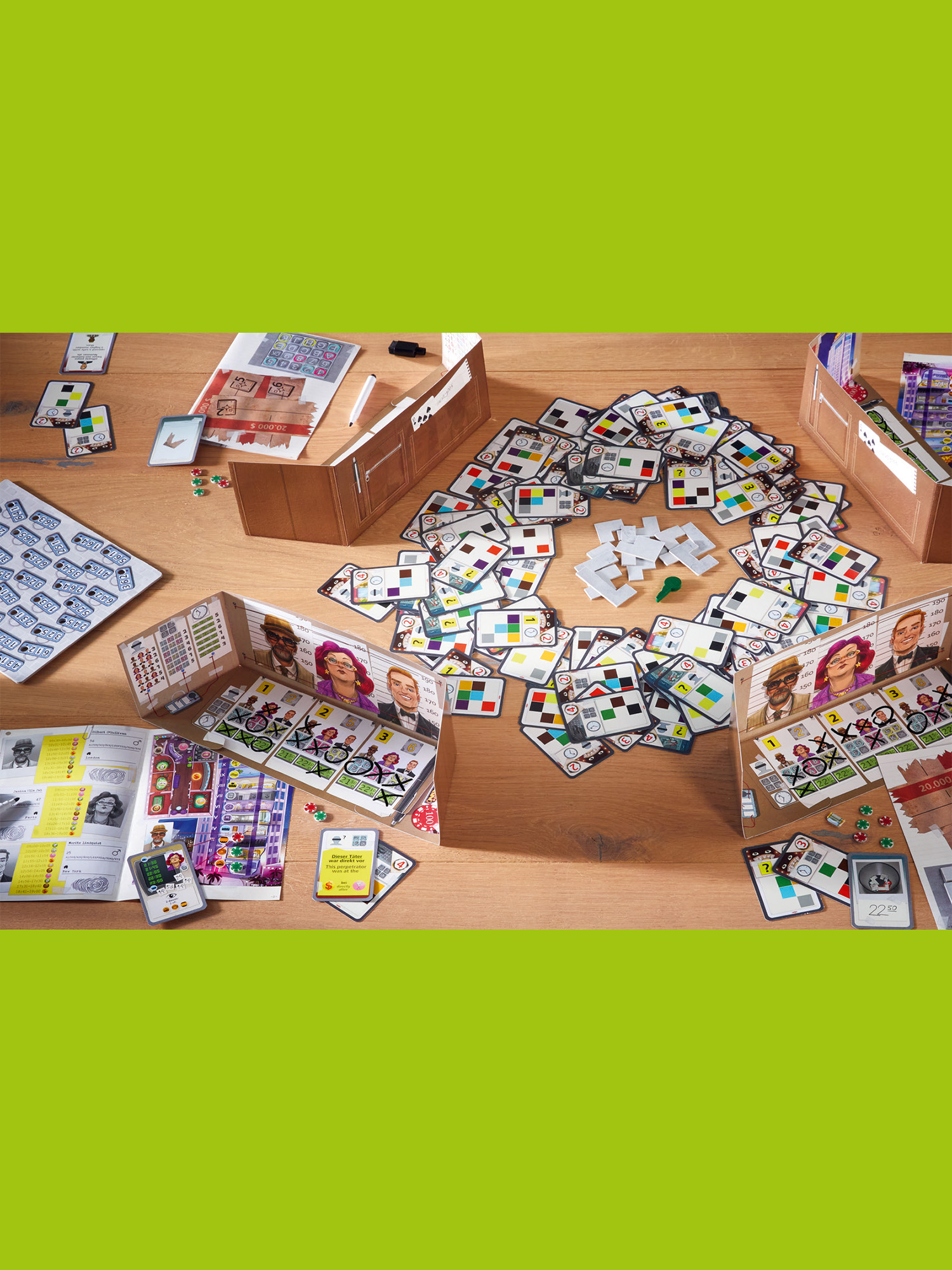 Brettspiel-Setup auf einem Holztisch. Karten, Spielsteine und Spielbretter sind angeordnet. Braune Boxen und ein grüner Würfel sind sichtbar.