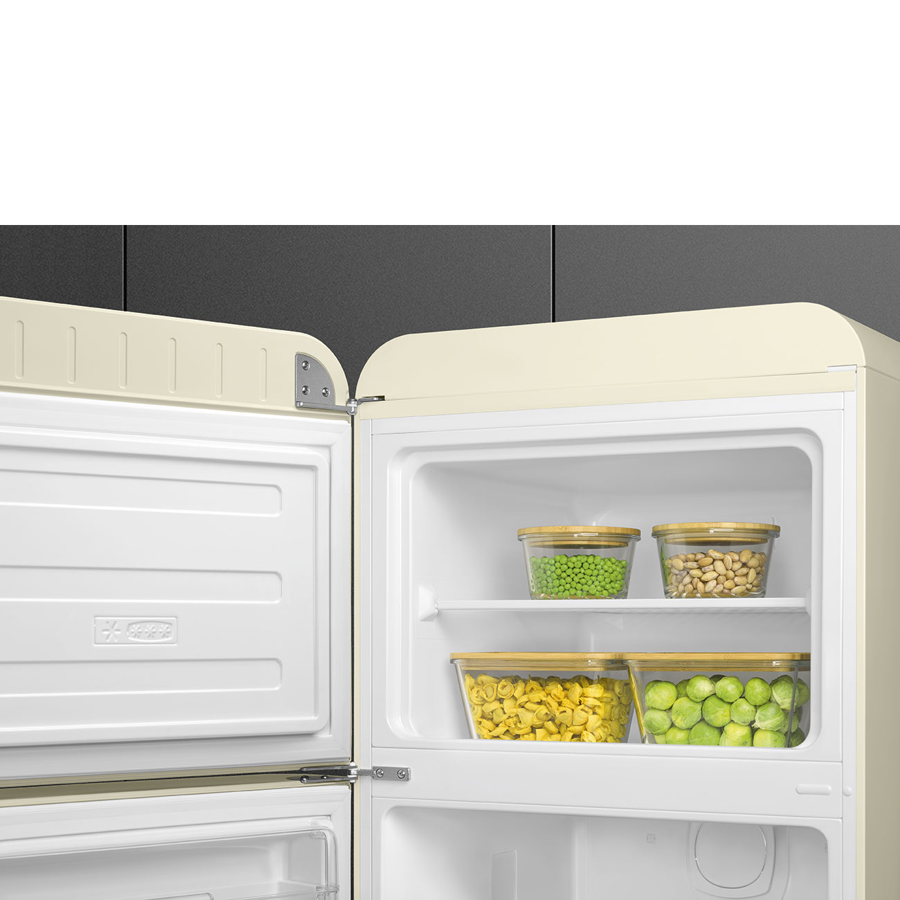 Offener Kühlschrank mit Behältern. Erbsen, Bohnen, Tortellini und Rosenkohl sind sichtbar. Kühlschrank ist cremefarben.