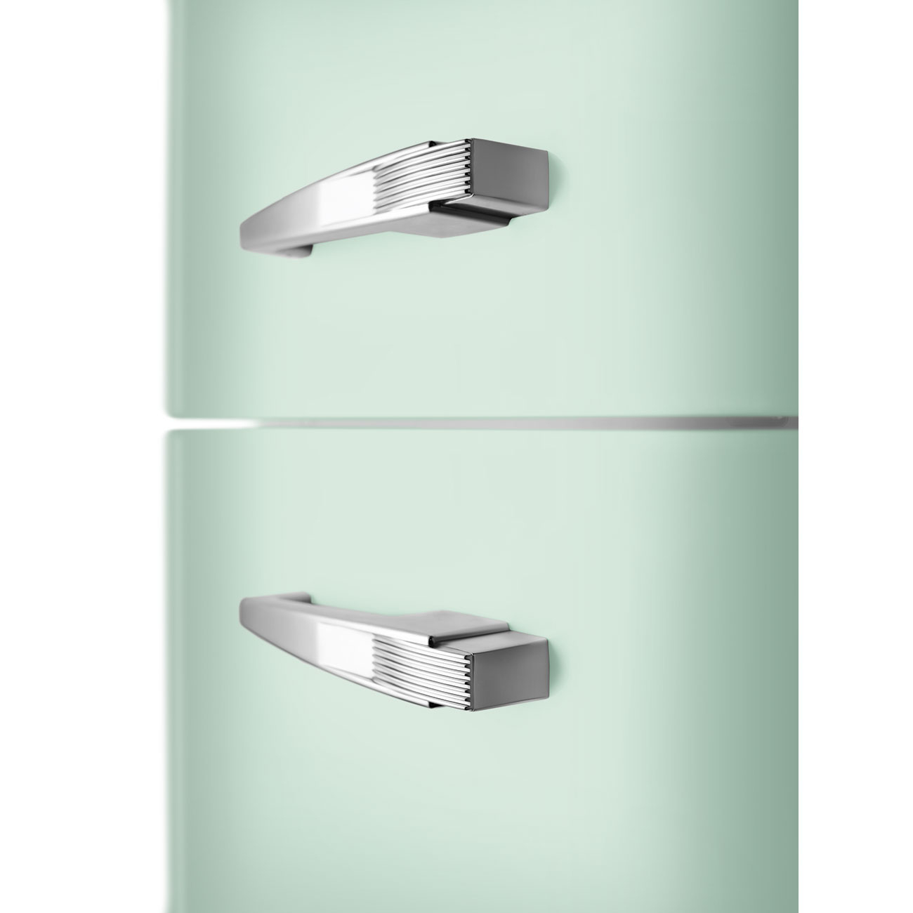 Primer plano de un refrigerador verde claro con dos manijas plateadas. Las secciones superior e inferior están separadas por una línea horizontal.