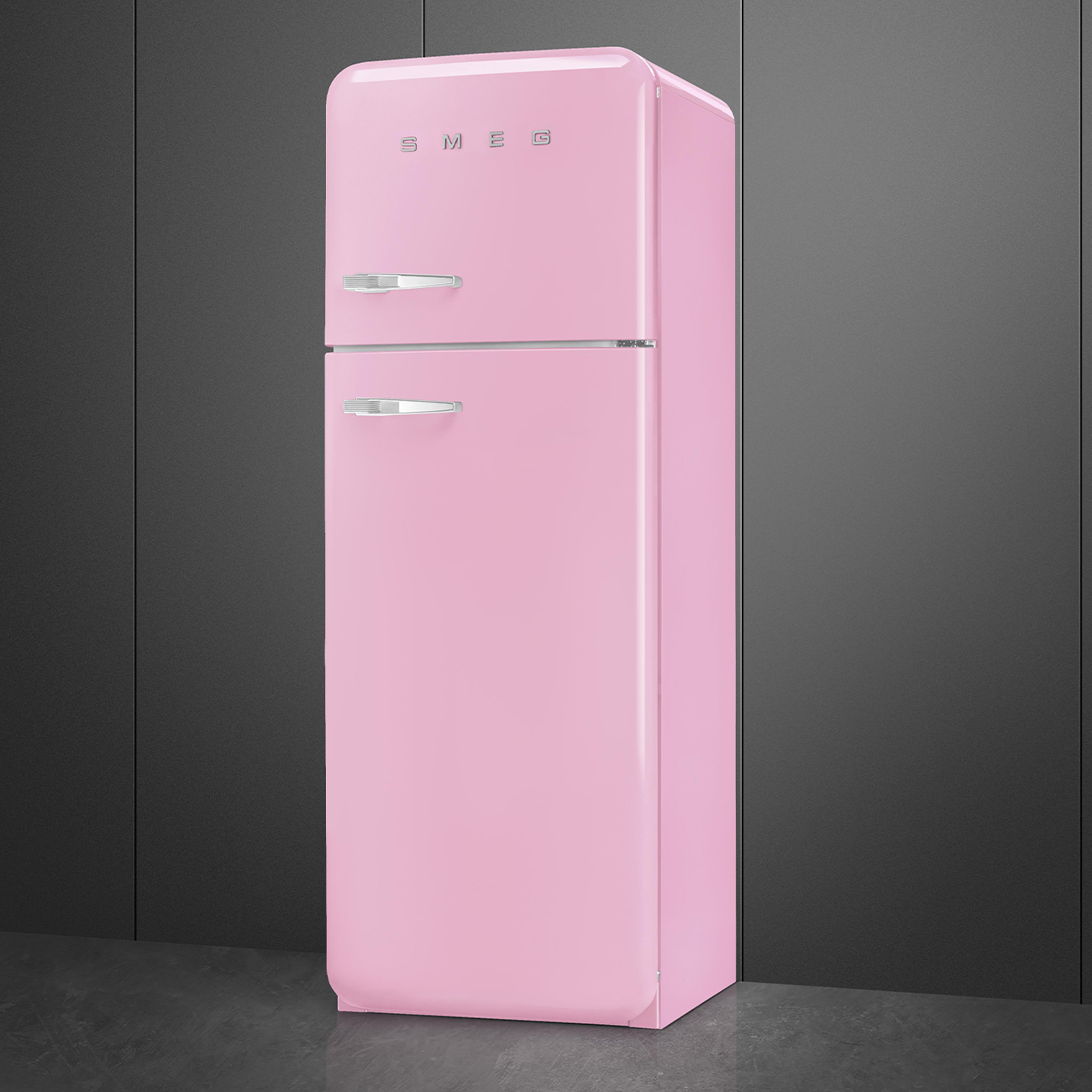 Un refrigerador Smeg rosa sobre fondo gris oscuro. Tiene diseño retro, manijas plateadas y el logo Smeg en la parte superior.