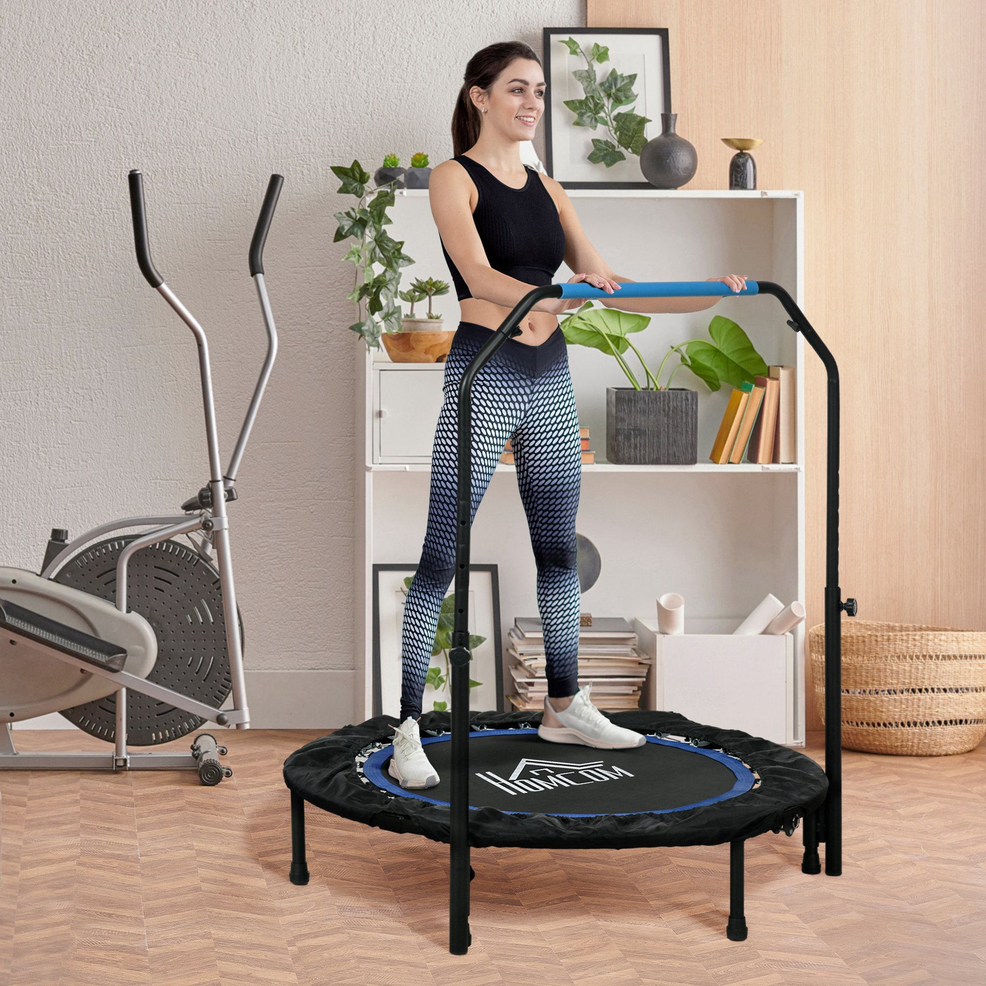 Mujer en trampolín con barra de apoyo. Máquina elíptica a la izquierda. Estantes y plantas en el fondo. Suelo de madera.