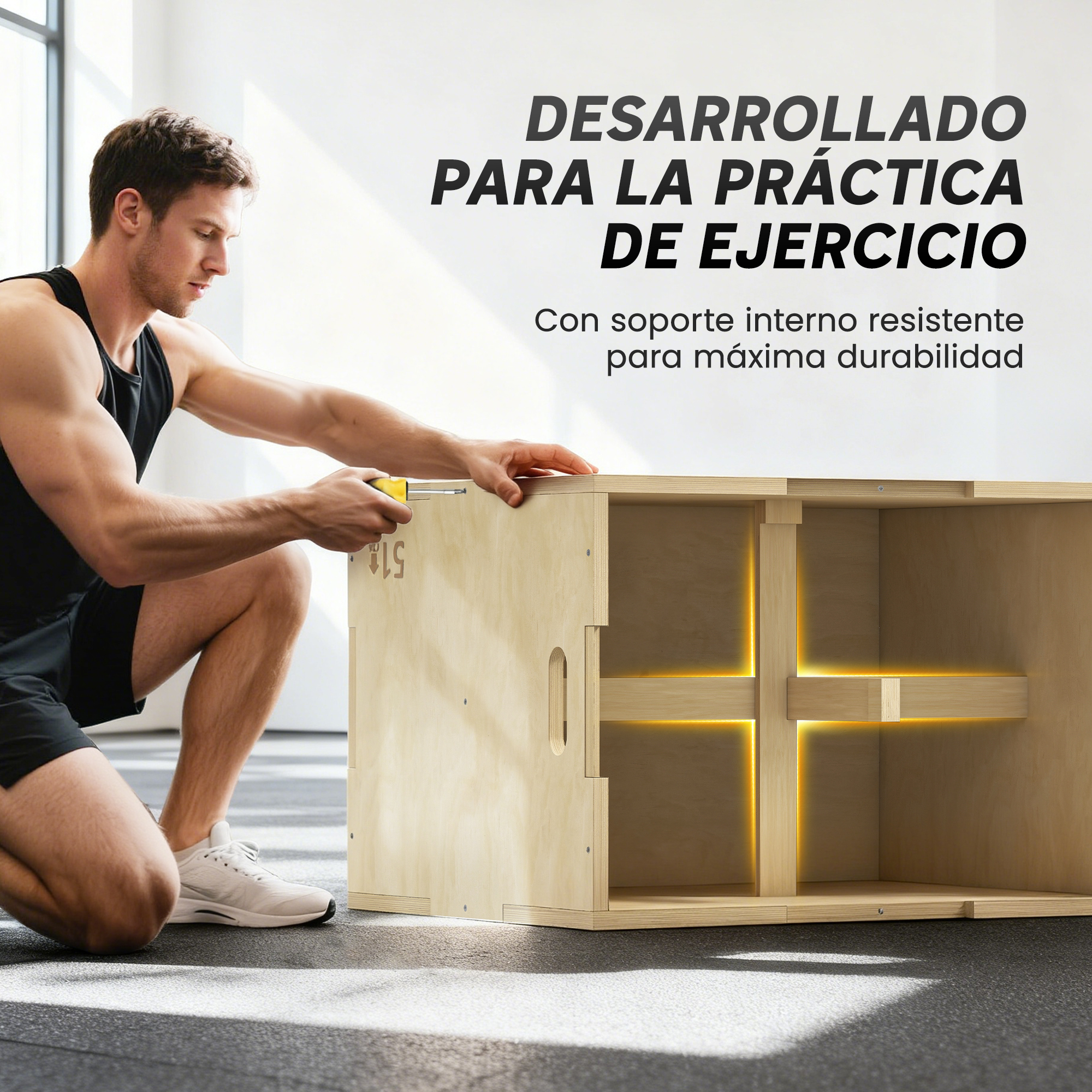 Un hombre se agacha junto a una caja de ejercicios de madera. El texto en la pared dice 'Desarrollado para la práctica de ejercicios'.