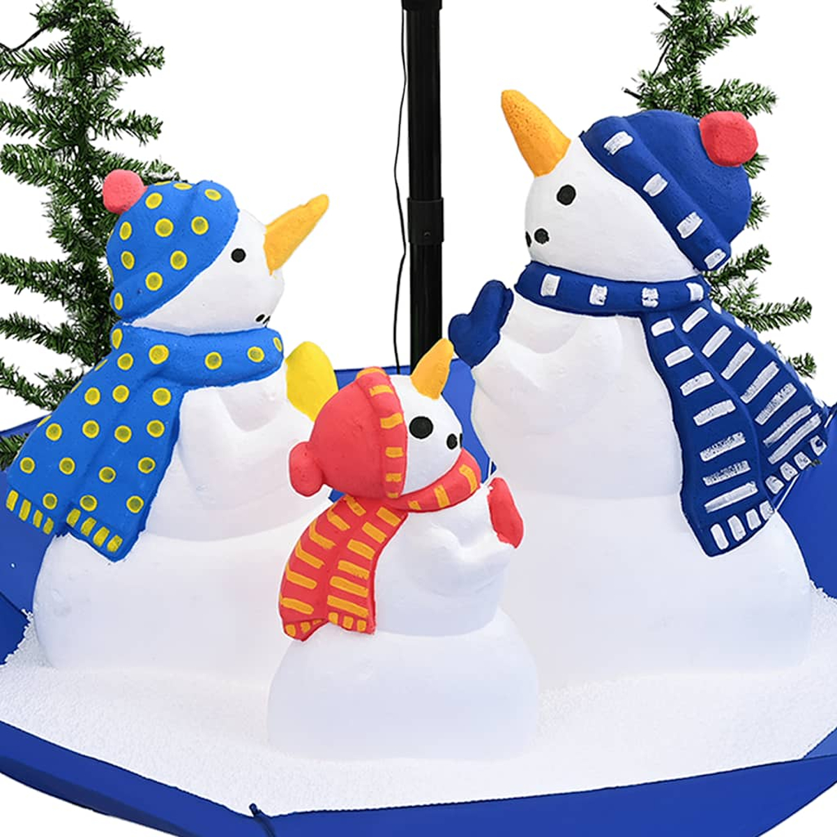 Drei Schneemänner mit Mützen und Schals stehen auf einer verschneiten blauen Oberfläche. Tannenzweige und eine schwarze Stange sind im Hintergrund.