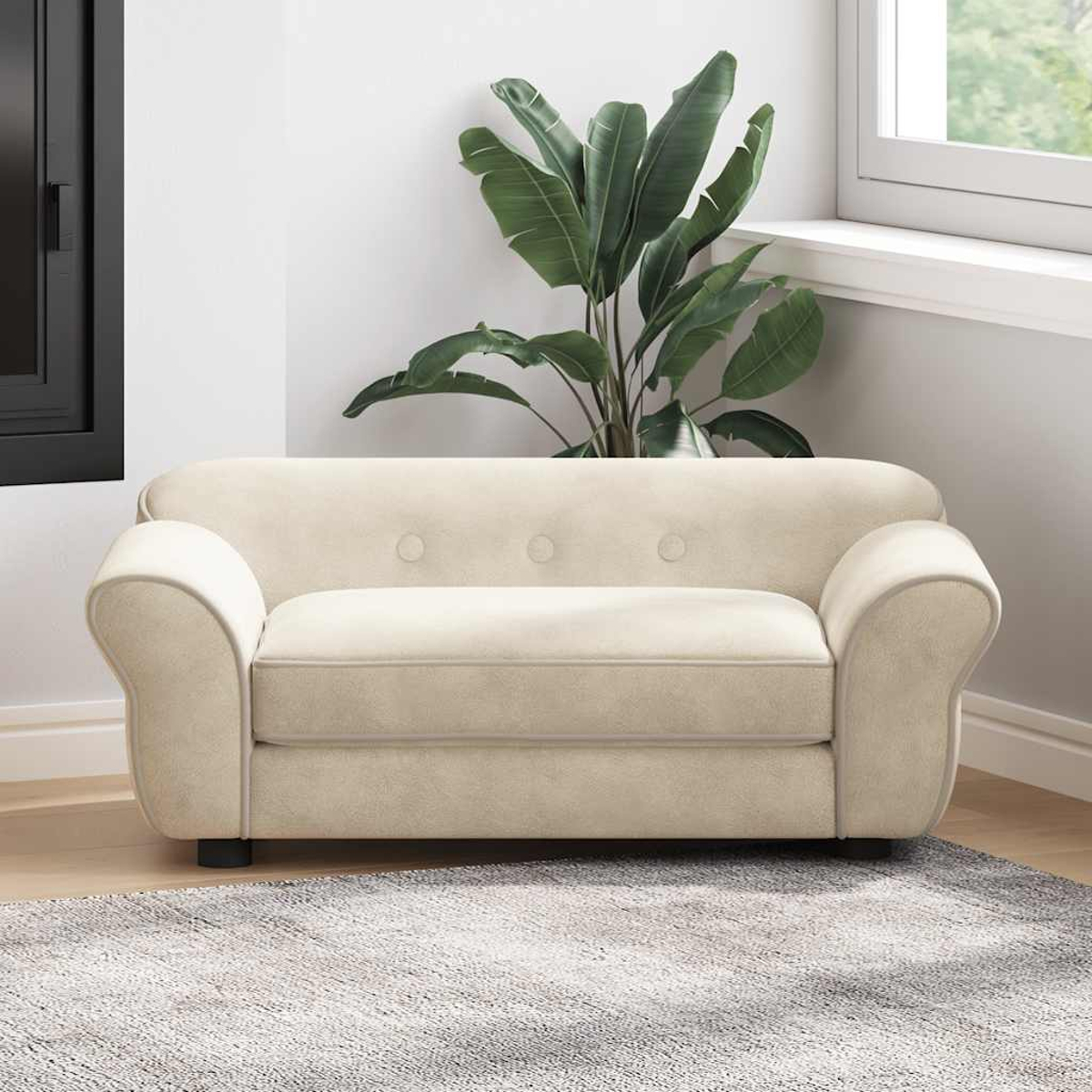 Cremefarbenes Sofa mit geschwungenen Armlehnen. Eine große grüne Pflanze steht dahinter. Das Sofa steht auf einem gemusterten Teppich, in der Nähe eines Fensters.