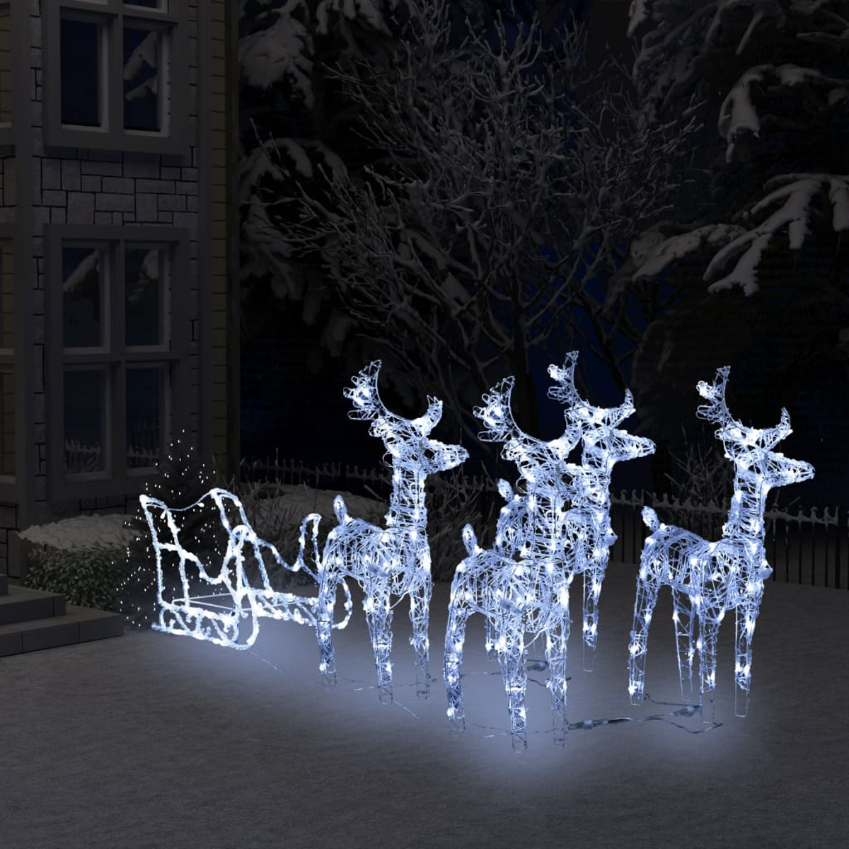 Leuchtende Rentiere und ein Schlitten auf einem verschneiten Rasen vor einem Haus, Winterszene. Weihnachtsdekoration.