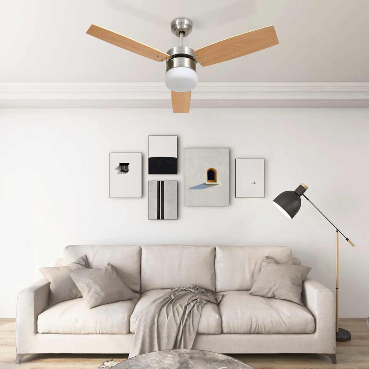 Salón con ventilador de techo, arte, sofá y lámpara de pie. El ventilador tiene aspas de madera. El sofá tiene almohadas y una manta.