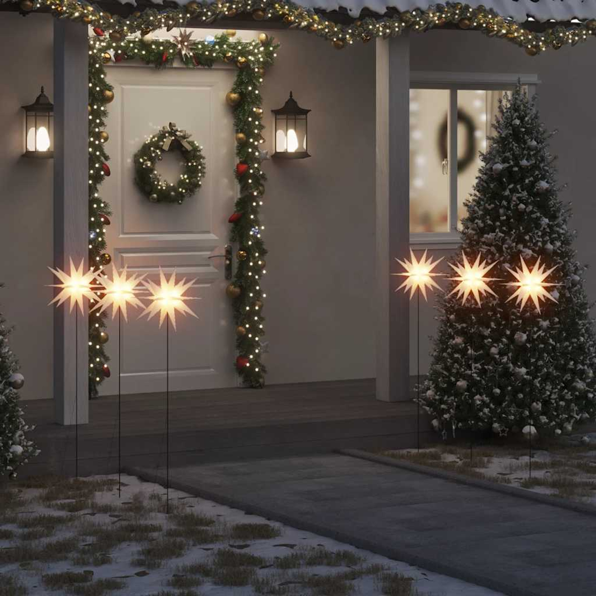Ein Hauseingang weihnachtlich geschmückt. Sternförmige Lichter im Hof. Eine Tür hat einen Kranz. Ein Weihnachtsbaum rechts.