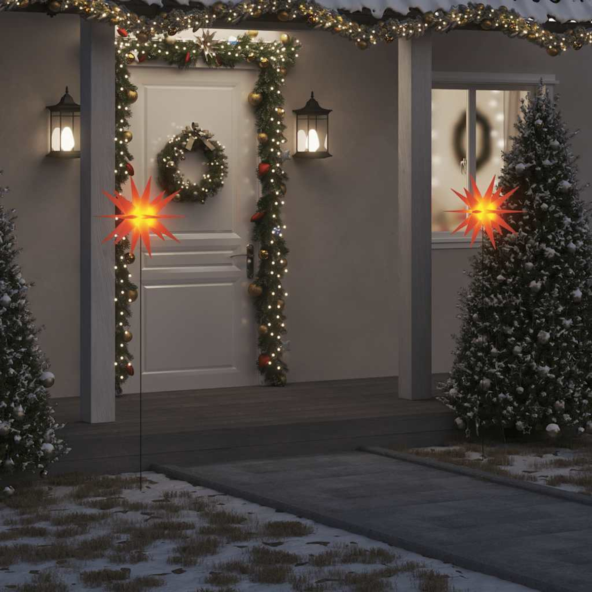 Ein Hauseingang weihnachtlich geschmückt. Zwei Sternlichter, Girlanden, Kränze, Lichter, schneebedeckte Bäume und ein Weg sind sichtbar.