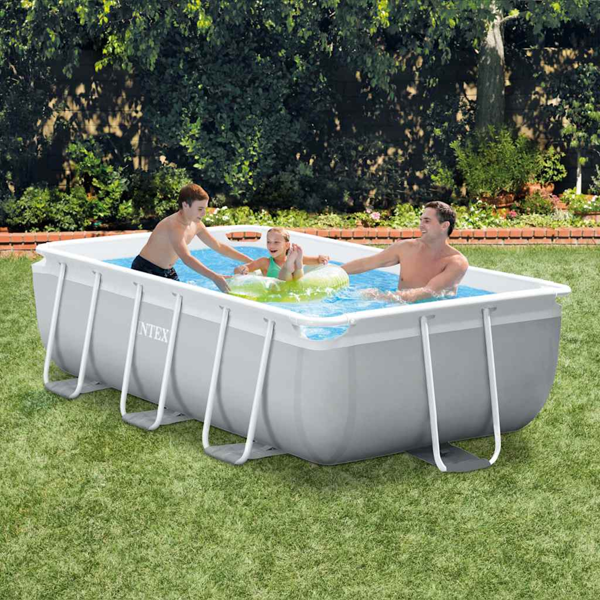 Drei Personen in einem rechteckigen Pool, zwei Erwachsene und ein Kind. Das Kind befindet sich in einem aufblasbaren Ring. Umgeben von Gras und Blättern.