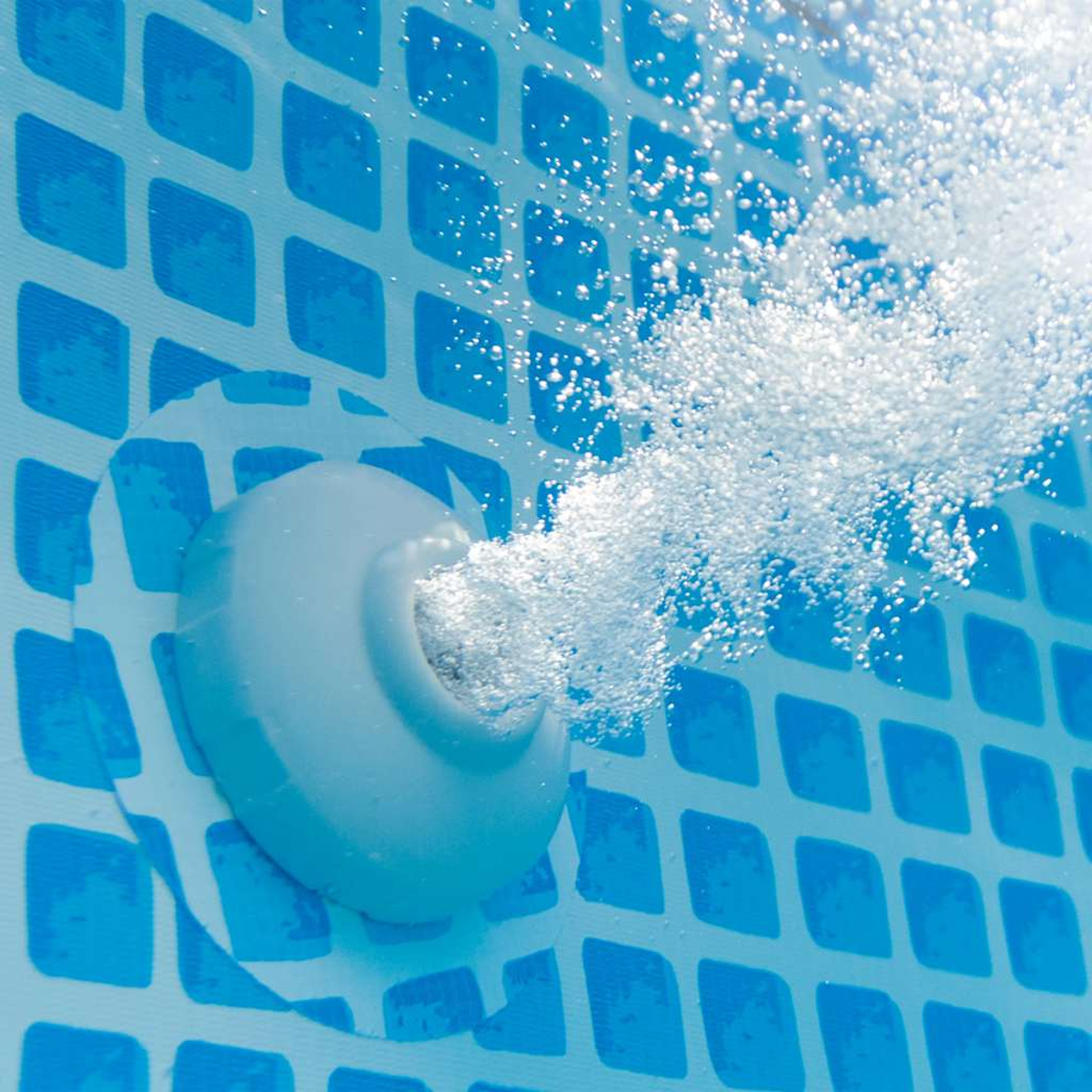 Nahaufnahme eines Pool-Wasserauslasses, der Blasen ins Wasser ausstößt. Die Poolwände haben ein blaues geometrisches Muster.