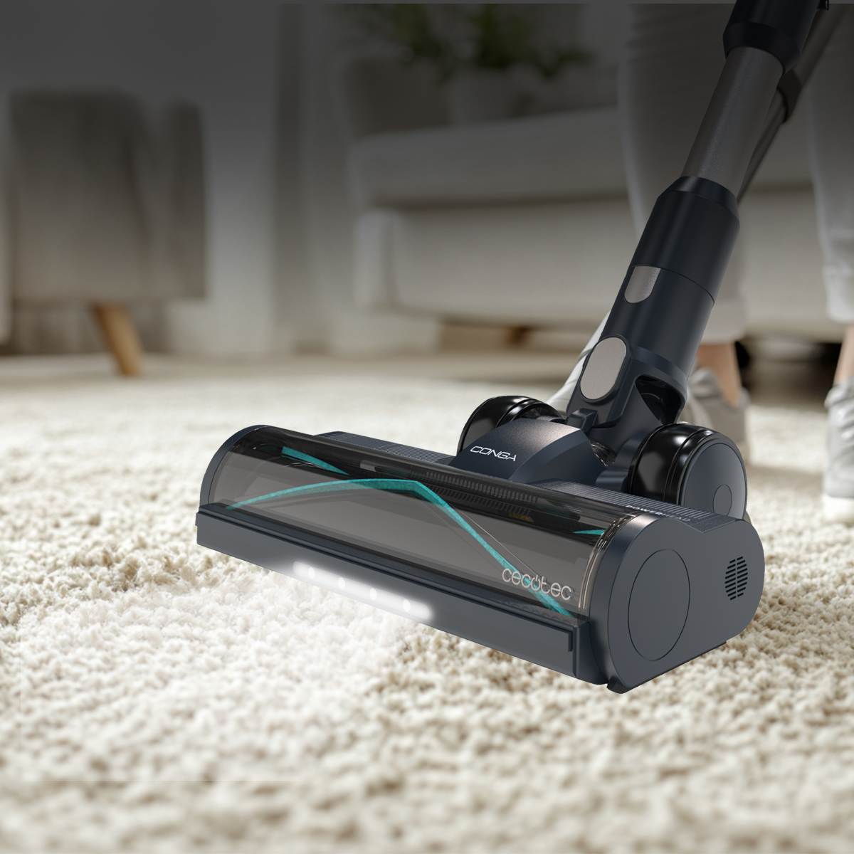 Una persona che aspira un tappeto bianco con un aspirapolvere nero e grigio. La testina dell'aspirapolvere è vicina al tappeto.