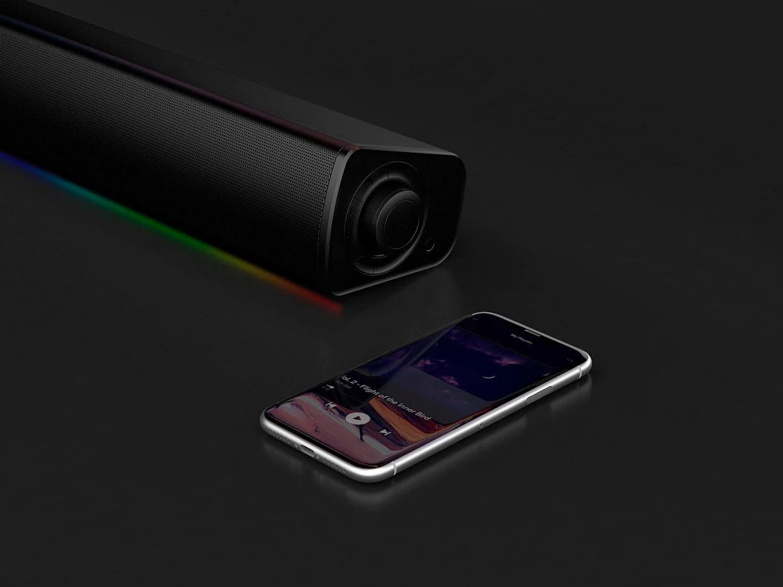 Una soundbar nera con luci colorate e uno smartphone che riproduce musica su una superficie scura.