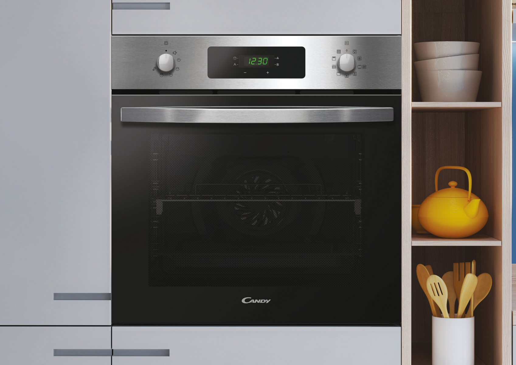 Horno de acero inoxidable con pantalla digital, junto a estantes de madera con cuencos, tetera amarilla y utensilios.