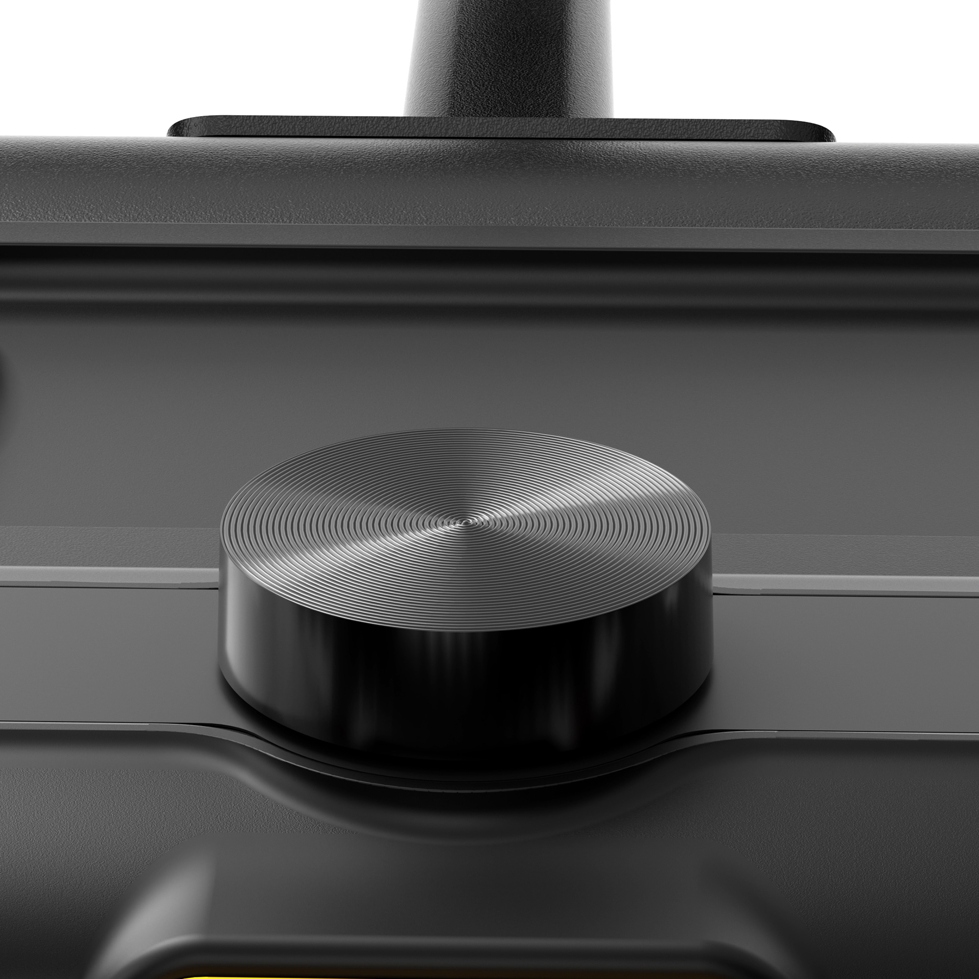 Primer plano de un dispositivo negro con una perilla de control circular y plateada. La perilla tiene detalles de círculos concéntricos. Fondo negro.