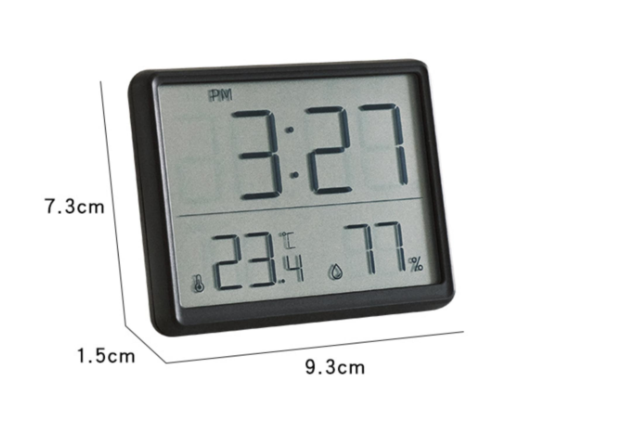 Eine Digitaluhr zeigt 15:27 Uhr, 23,4°C und 77% Luftfeuchtigkeit auf einem rechteckigen Gerät mit schwarzem Rahmen.