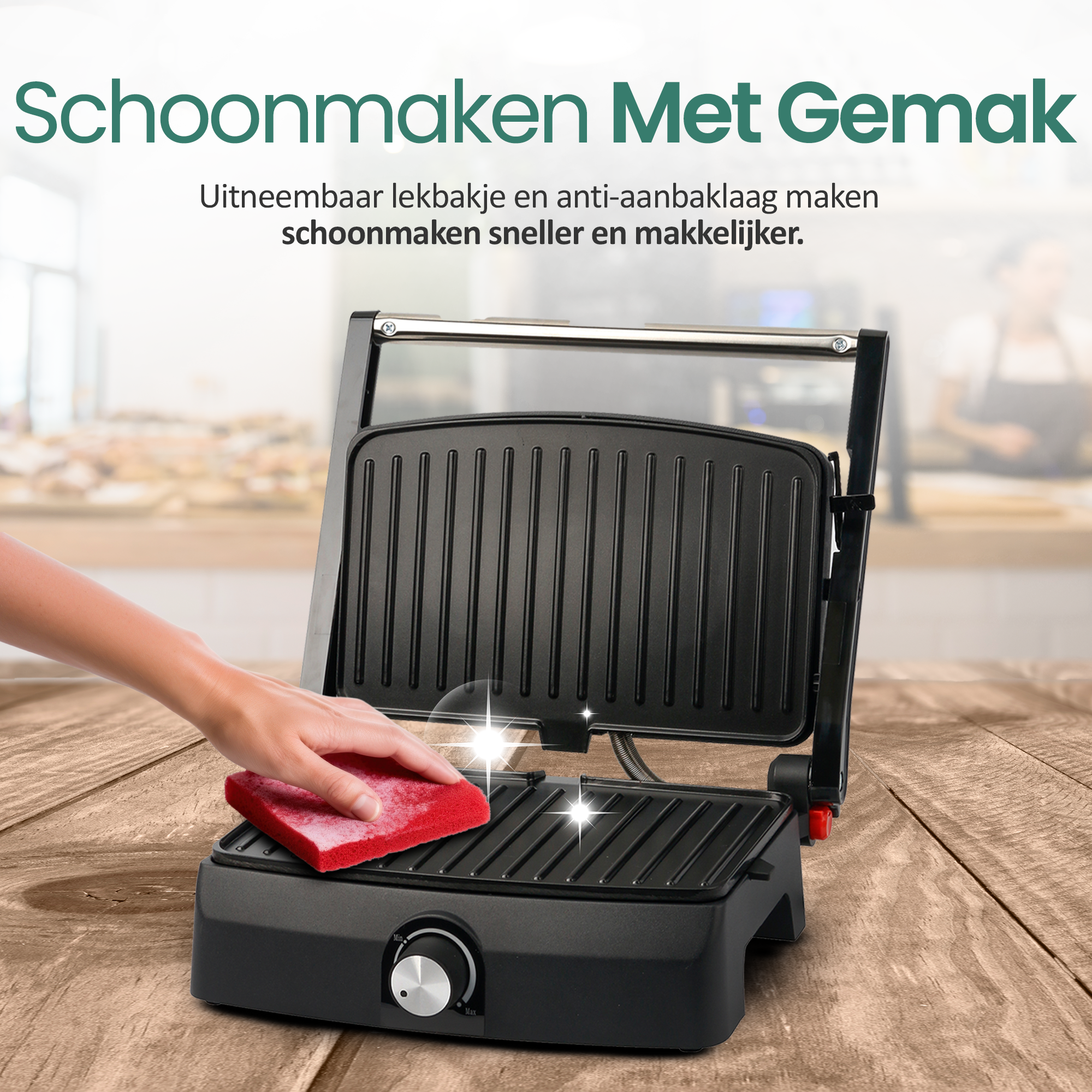 Eine Hand reinigt einen schwarzen Grill mit einem roten Schwamm auf einem Holztisch. Der Hintergrund ist unscharf.