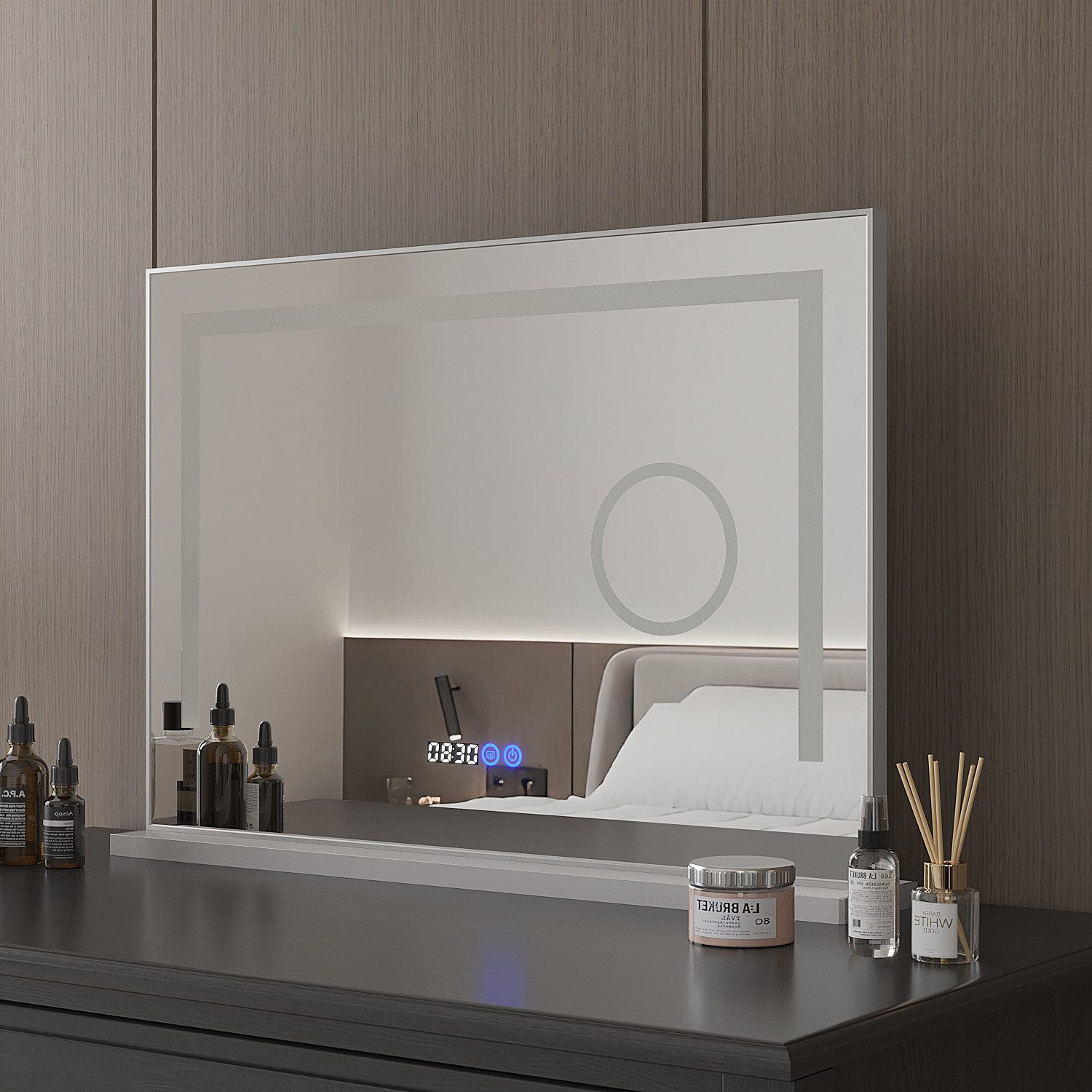 Ein moderner Spiegel spiegelt eine Schlafzimmerszene wider. Flaschen, ein Glas und ein Diffusor stehen auf einer dunklen Oberfläche.