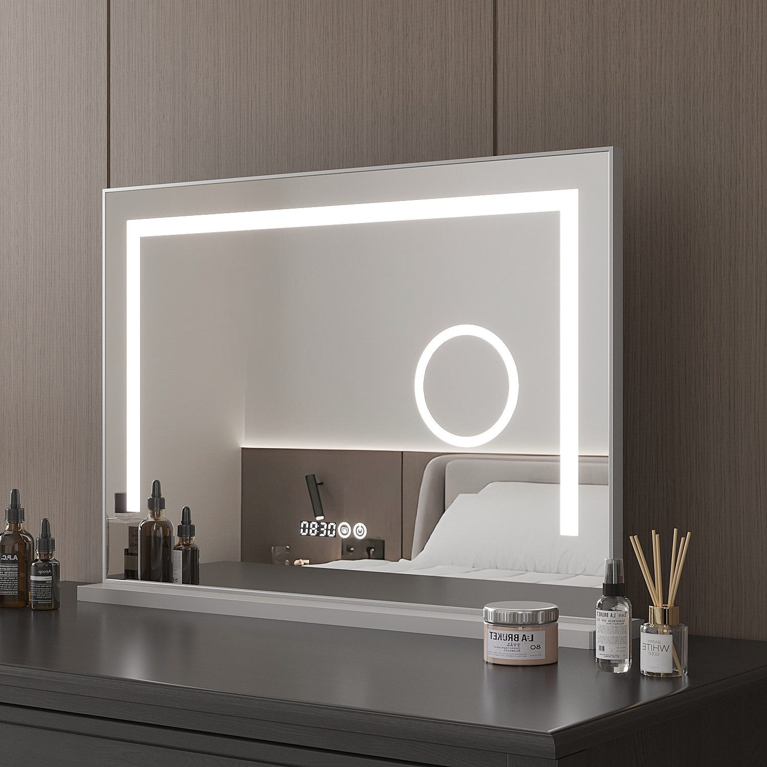 Ein beleuchteter Schminkspiegel mit digitaler Uhr-Reflexion. Eine Kommode enthält Kosmetikartikel. Der Hintergrund umfasst ein Bett und eine Holzwand.